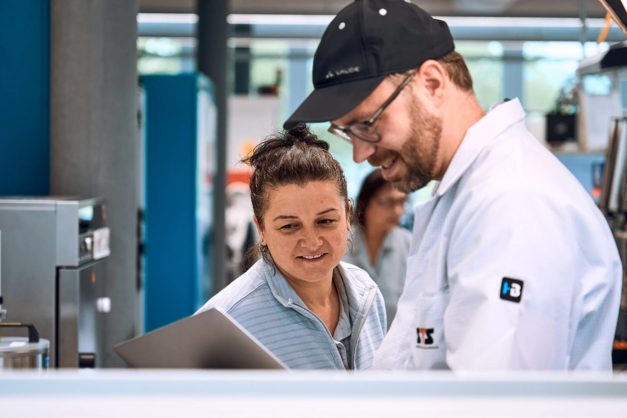 Professioneller Industriefotograf im Gespräch mit zufriedener Mitarbeiterin – authentische Momentaufnahme, die Vertrauen, Kommunikation und ein starkes Gespür für Menschen in industriellen Arbeitswelten zeigt.