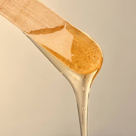 A wooden spatula with honey dripping from it.