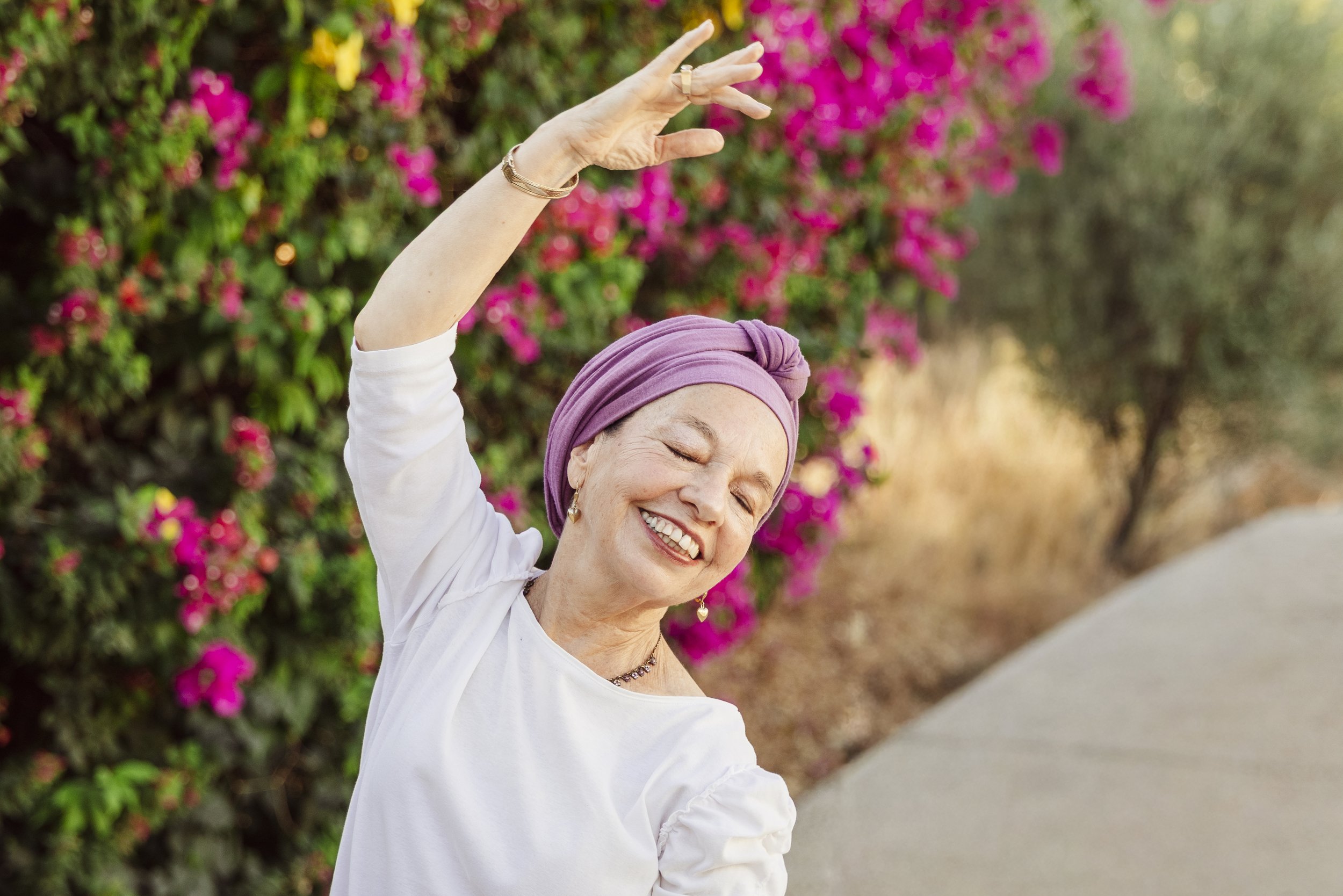 woman on white dress, dancing, smiling, in a natural environment