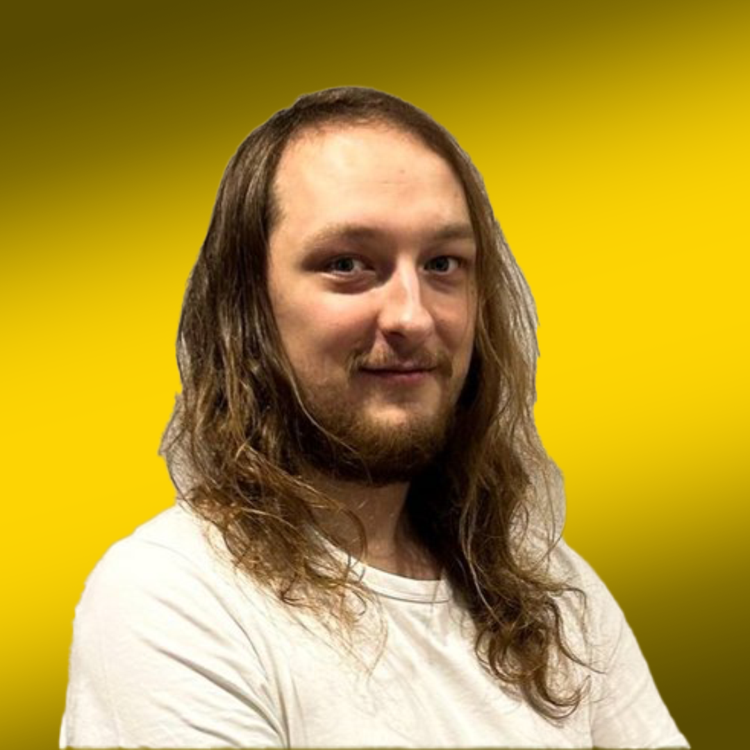 Person with long hair and a beard wearing a white t-shirt against a yellow background.