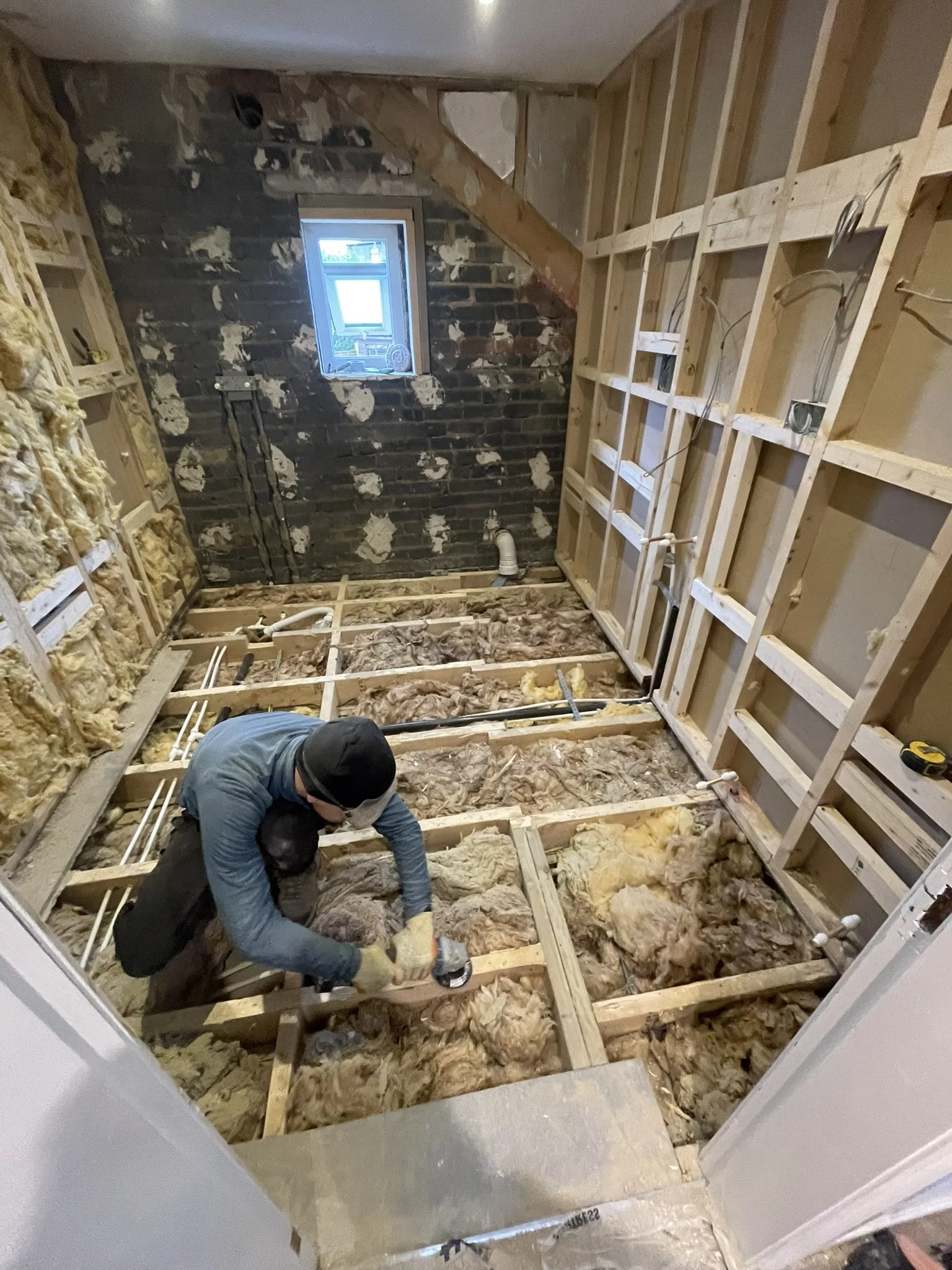 Complete bathroom renovation with floor preparation, structural framing and wall shimming to ensure level surfaces before installation.