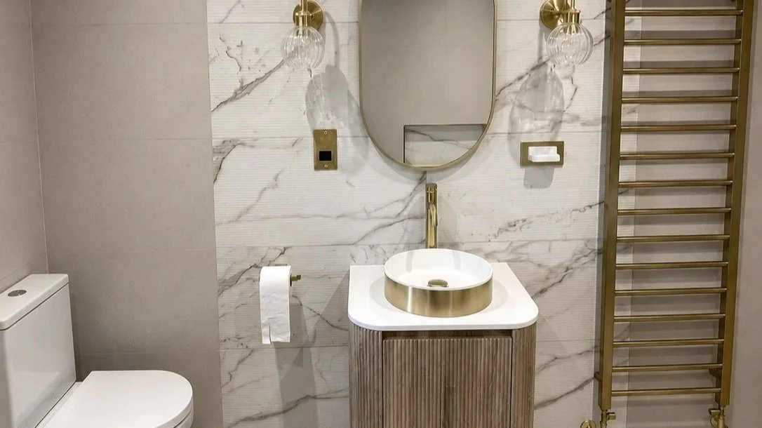 Luxury bathroom renovation featuring marble-effect tiles, brushed brass fixtures and bespoke installation by NWTI.