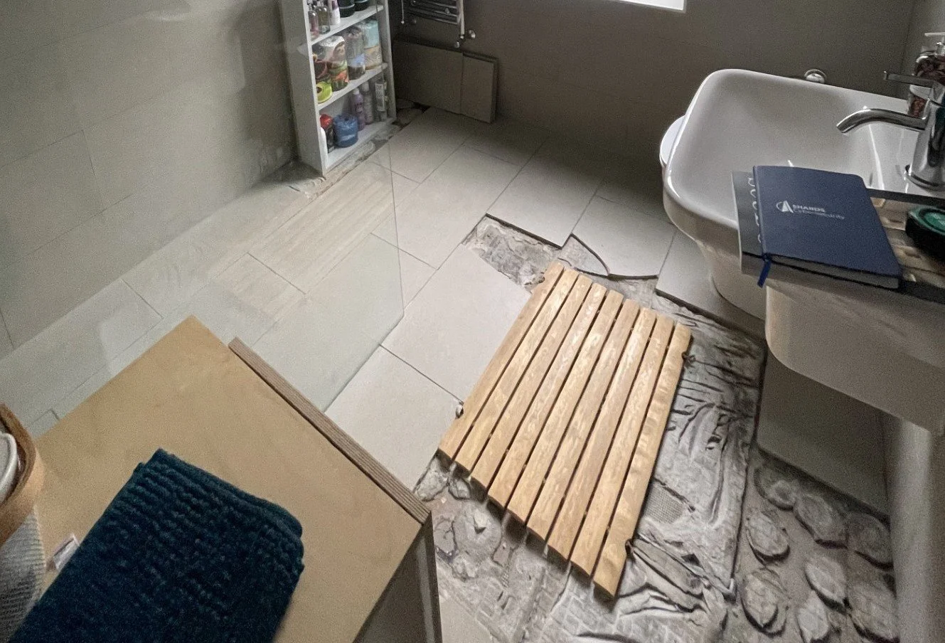 Bathroom floor with tiles removed to expose the damaged area during tile repair work.