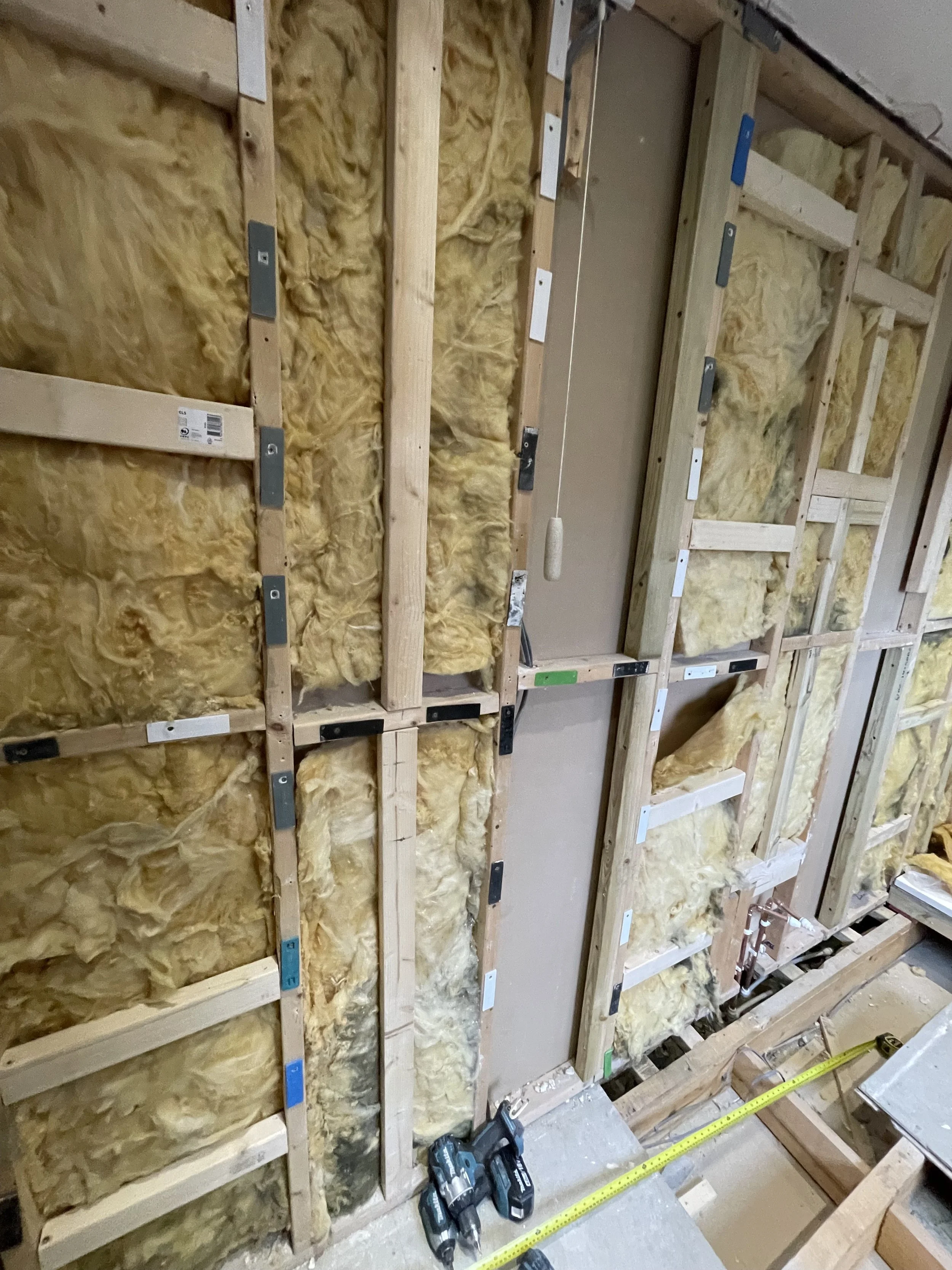 Bathroom renovation showing stud wall construction with precision wall shimming to create perfectly flat surfaces before boarding and tiling.