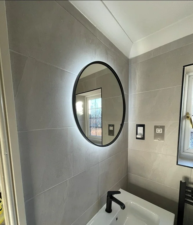 Contemporary bathroom renovation featuring large-format porcelain tiles, illuminated mirror and premium black brassware.