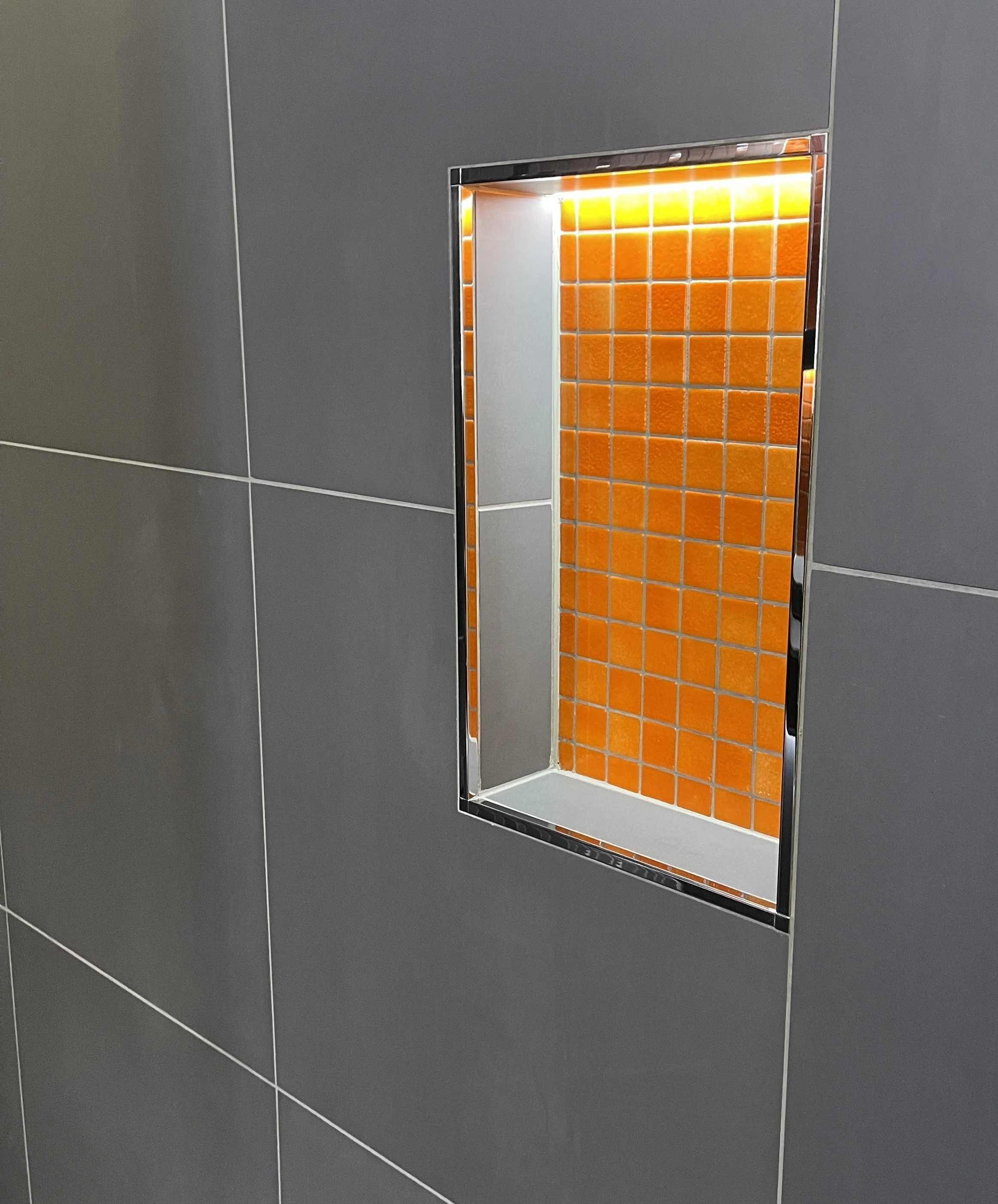 Illuminated shower niche demonstrating integrated LED feature lighting for contemporary bathroom design.