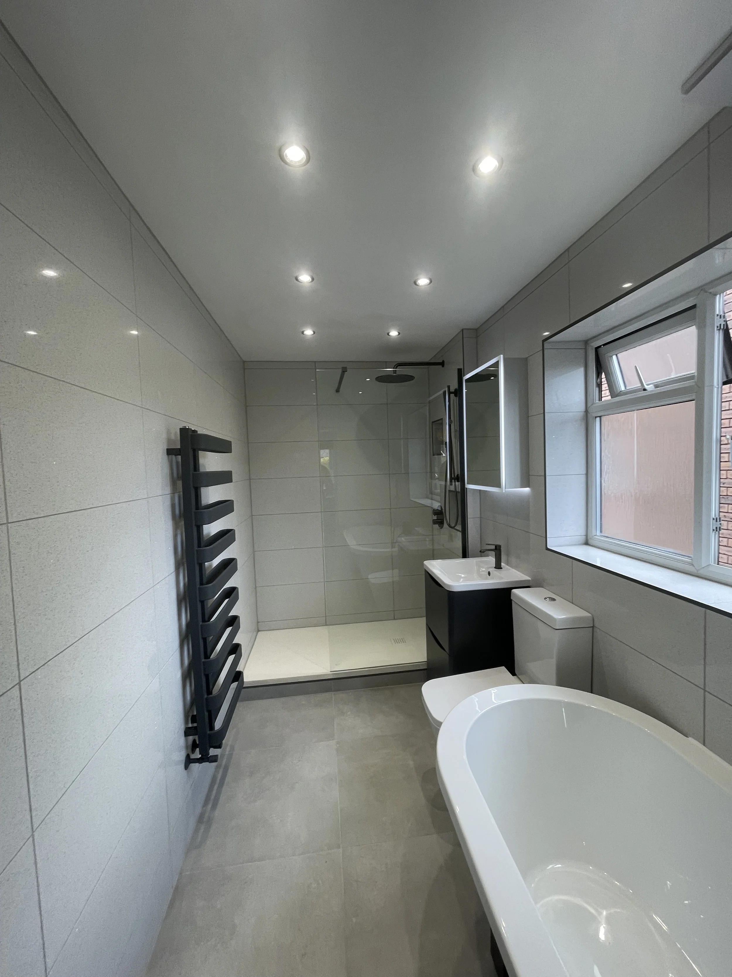 Luxury bathroom renovation featuring a freestanding bath, walk-in shower, illuminated mirror and designer radiator.