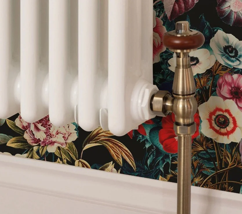 Contemporary radiator with brushed brass valves, professionally installed as part of a premium home renovation.