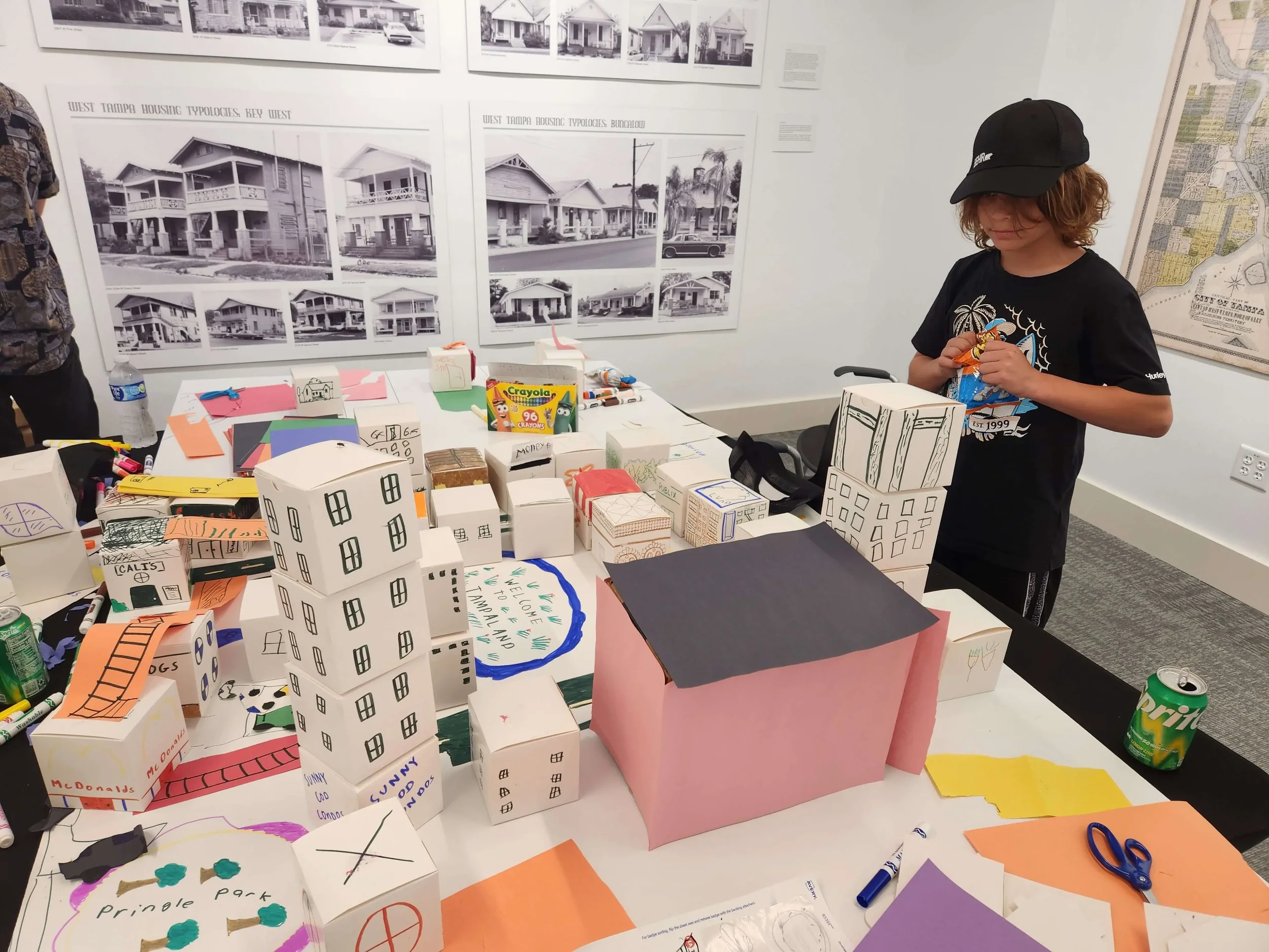 Colorful inflatable swim rings in yellow, pink, green, and blue, arranged on a metal frame with string lights, during dusk outdoors.