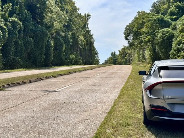 Historic Hooker Cut on Route 66 in Pulaski County, Missouri, showing the four-lane concrete roadway climbing through a deep limestone highway cut with vine-covered rock walls.