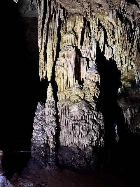 Large cave column with surrounding stalactites and stalagmites inside Fisher Cave in Missouri.