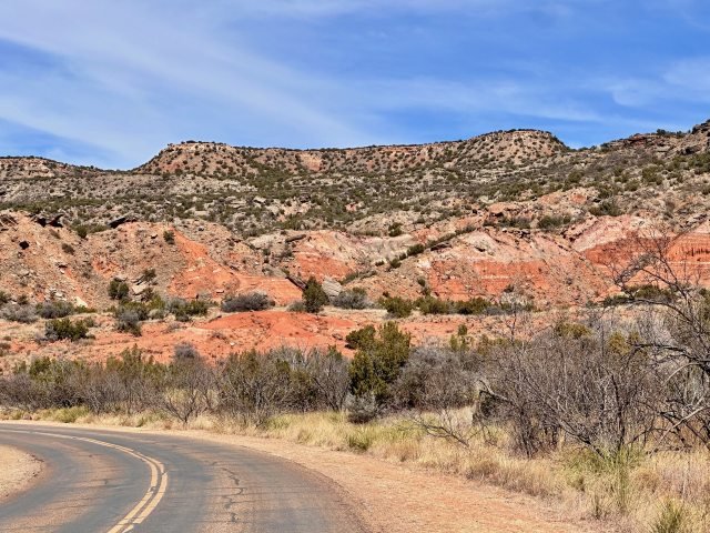Palo Duro Canyon mesa with striking red rock formations and trees in the foreground near the Mesquite Campground in Texas.