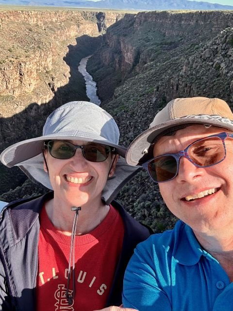 Couple taking a selfie with the Rio Grande Gorge in the background near Taos, New Mexico, showing the deep canyon and high‑desert landscape.