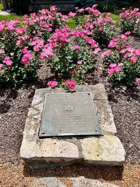 1981 time capsule marker at Shelter Gardens in Columbia, Missouri, set among landscaped flowers and greenery