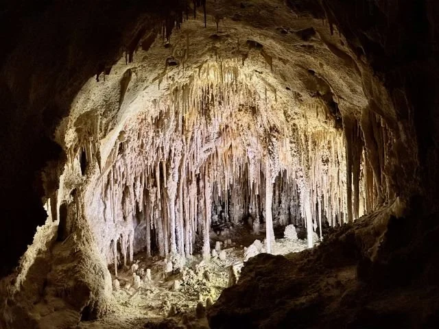 Carlsbad Caverns limestone formations with stalactites hanging from the ceiling and stalagmites rising from the cave floor.