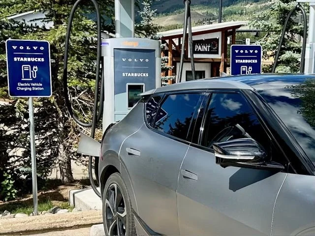 Gray Kia EV6 charging at a ChargePoint DC fast charger outside a Starbucks in Silverthorne, Colorado, during an electric vehicle road trip through the Rocky Mountains and western United States.