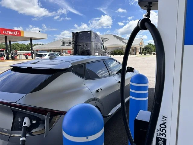 Kia EV6 electric car plugged into EVgo charging station at Pilot Flying J truck stop, with Flying J building and Denny’s restaurant sign visible behind it.