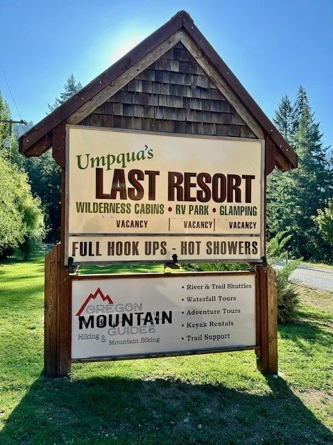 Entrance sign for Umpqua’s Last Resort on Oregon’s Umpqua Scenic Byway surrounded by lush forest.