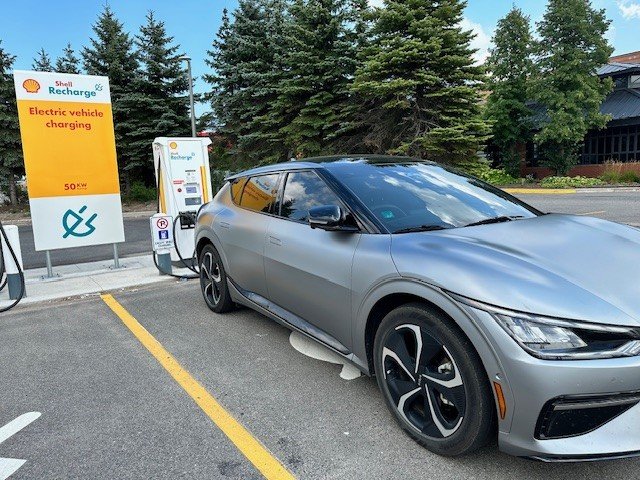 A matte grey KIA EV6 charging at a Shell Recharge station in Sault St. Marie, Ontario, Canada.