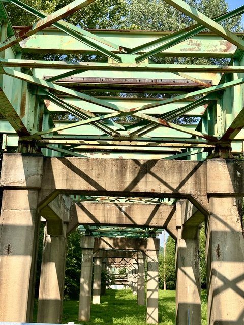 Concrete bridge piers and green steel supports of the historic Route 66 bridge crossing the Meramec River at Route 66 State Park in Missouri.