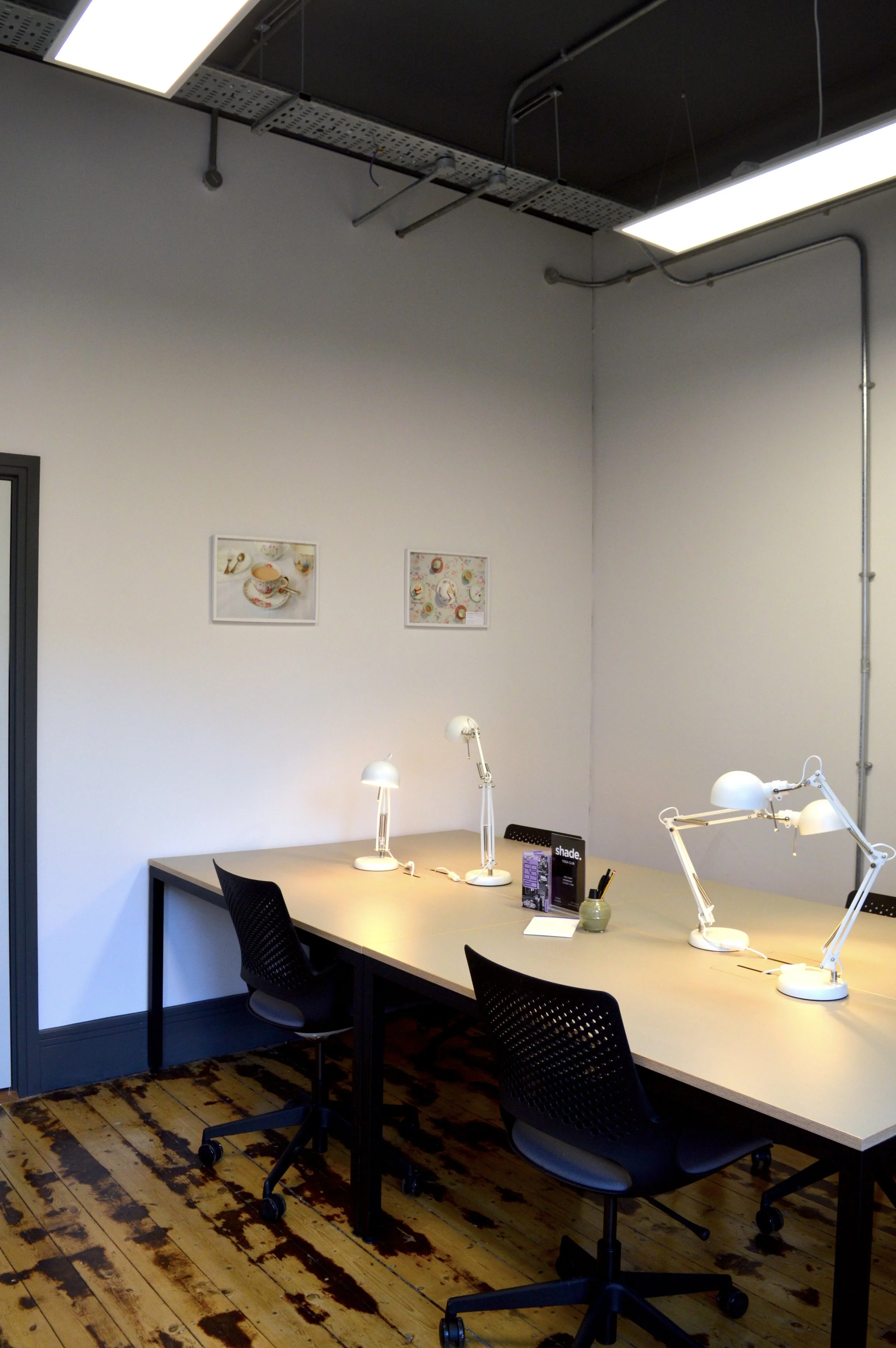 A workspace featuring a desk, framed photography on the walls by Shaw & Shaw, and wooden floors.