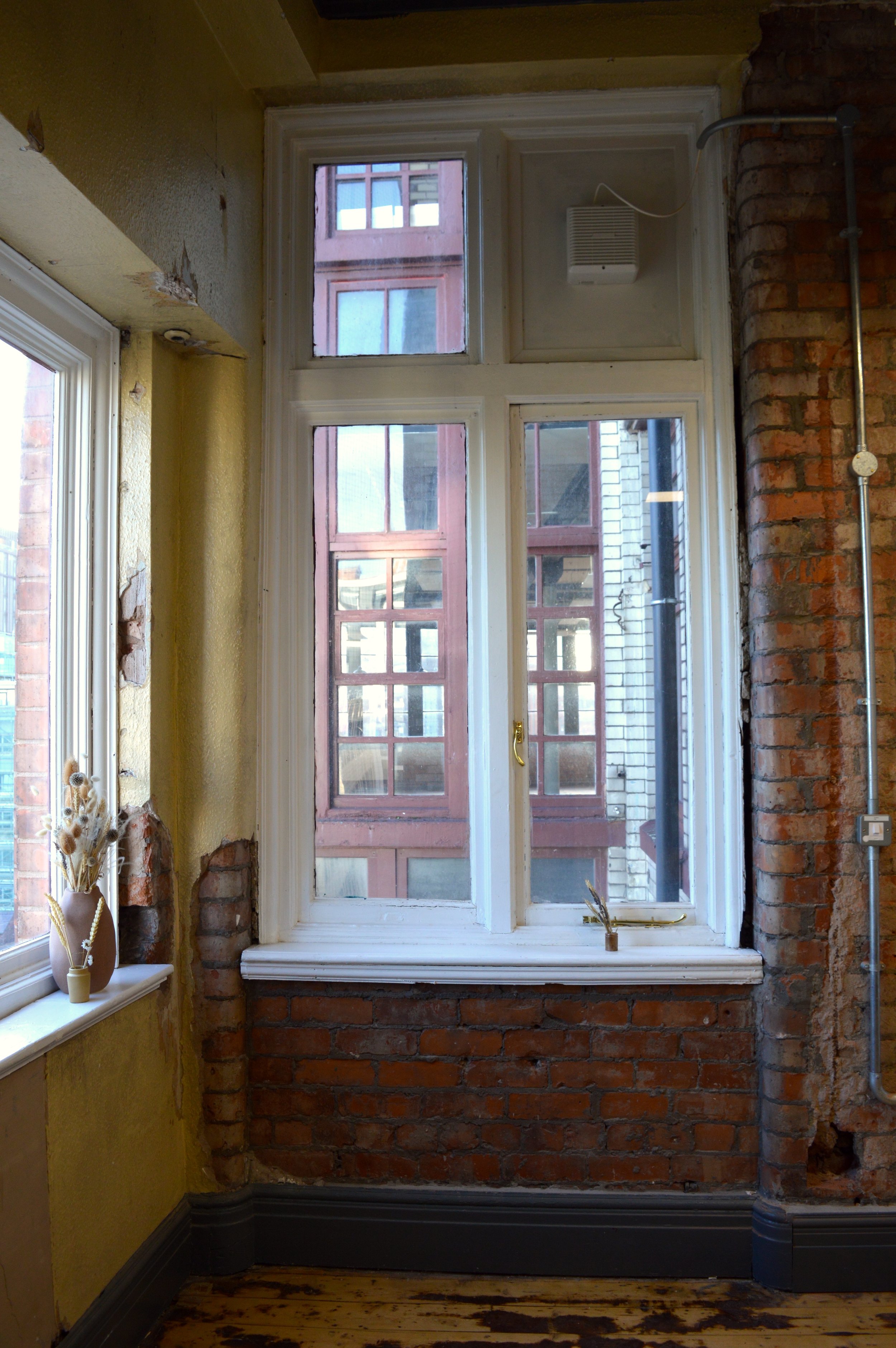 View from the window of a restored textile building, with original paint work and red brick walls.