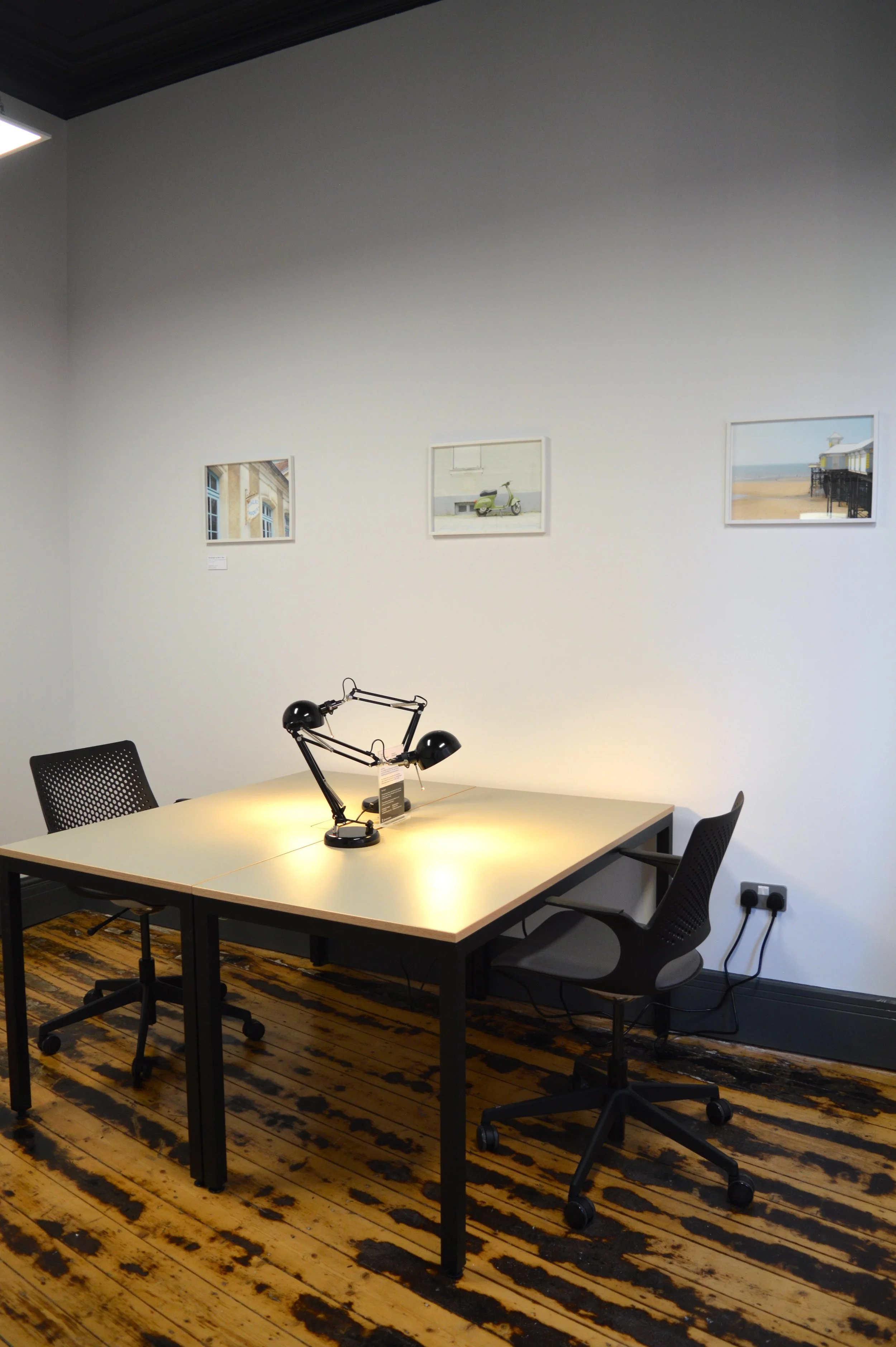 A desk in a private studio in SEESAW, with framed photography on the walls by Shaw & Shaw.