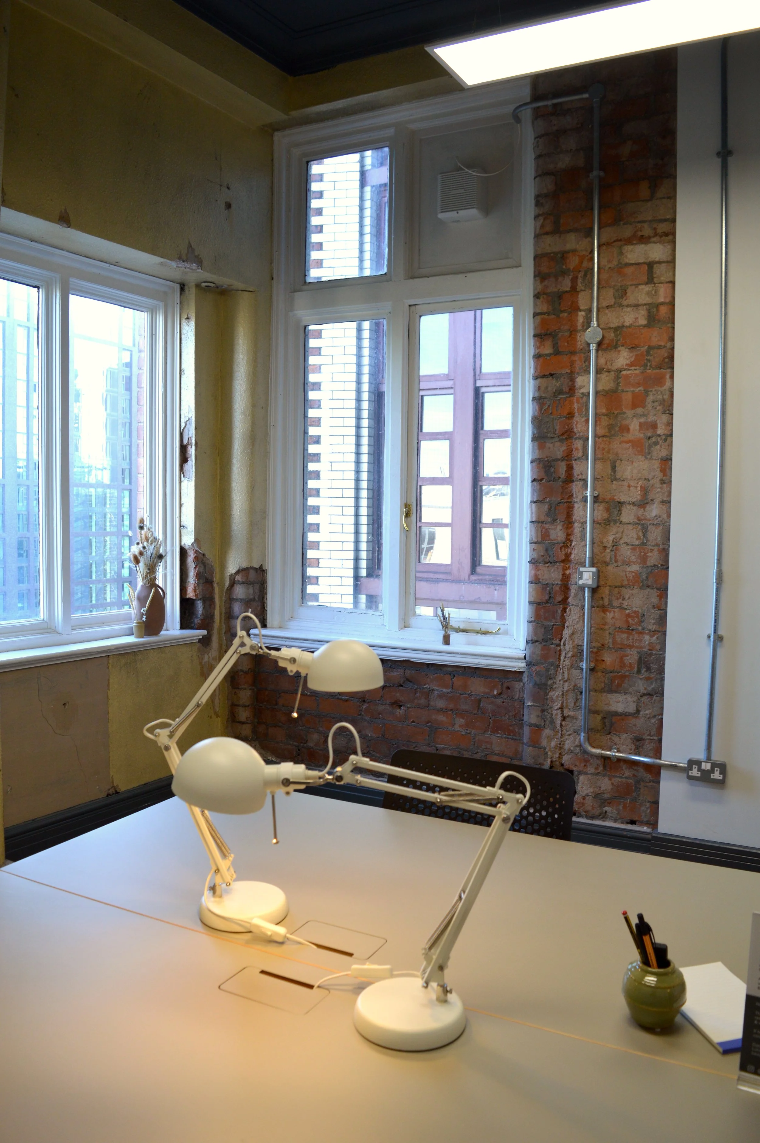A workspace within a historic building in Manchester, featuring red brick walls and original paintwork.