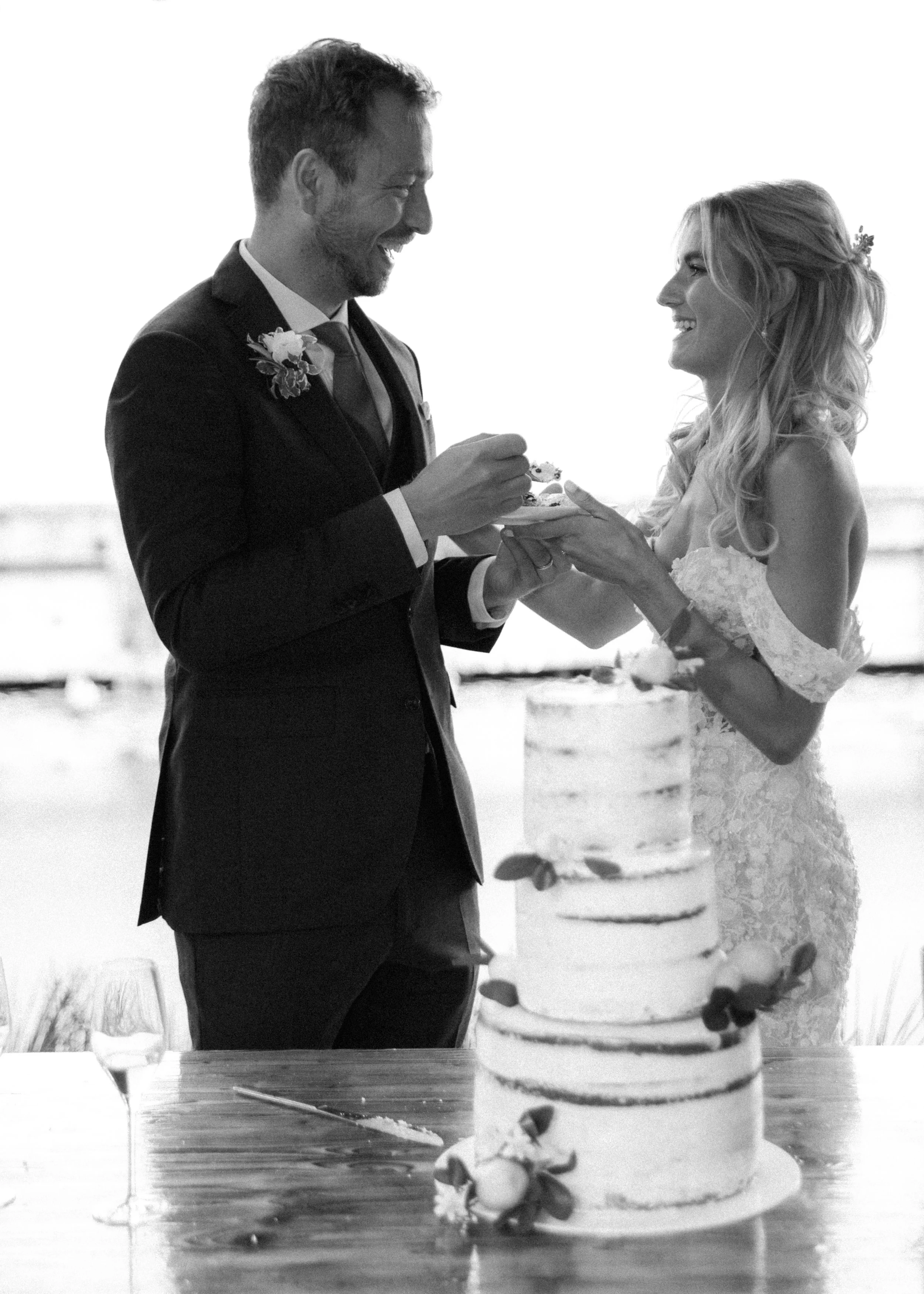Ein Brautpaar bei der Hochzeit, das beim Anschneiden der Hochzeitstorte ist, schwarz-weiß Foto.
