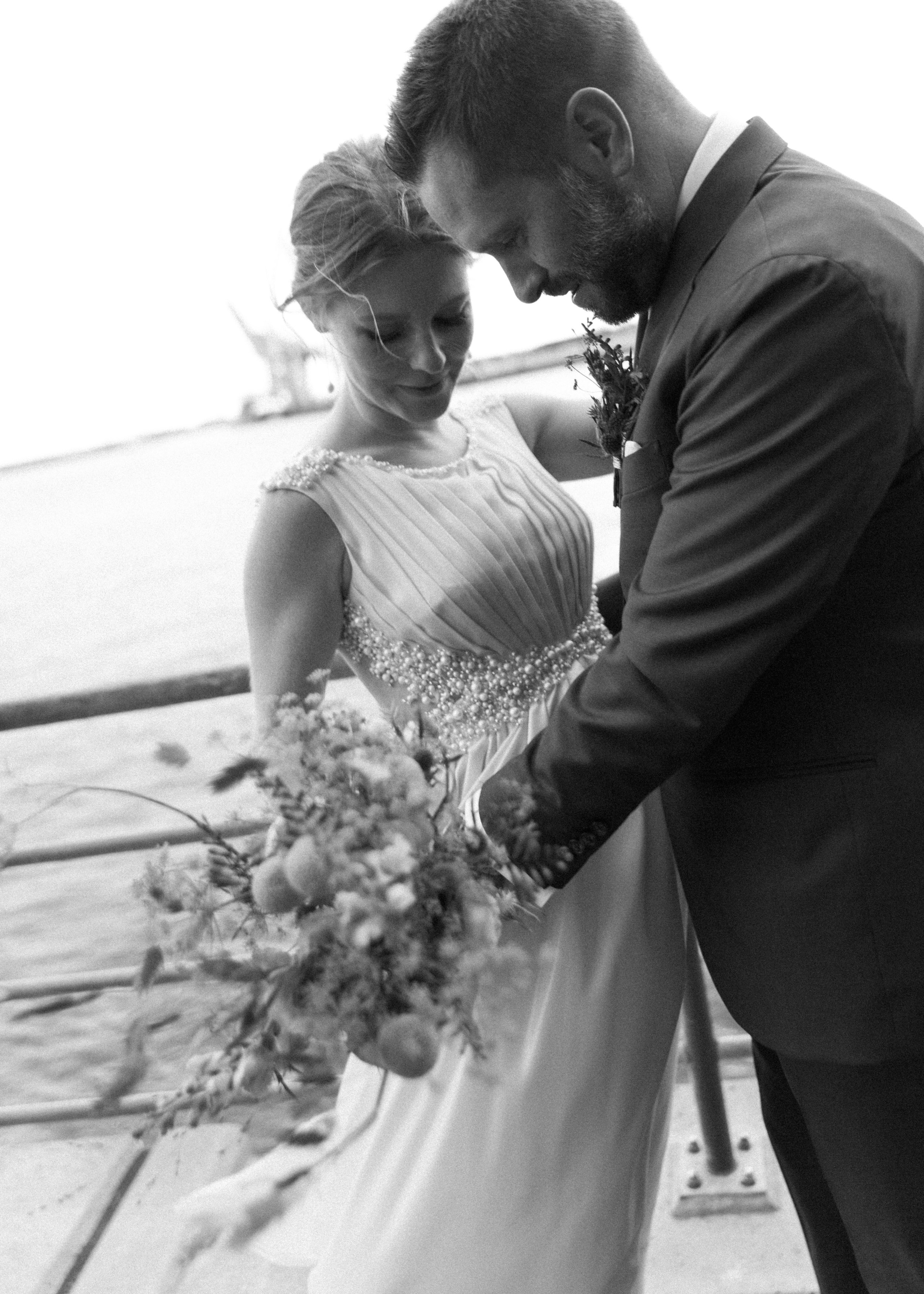 Braut und Bräutigam während der Hochzeit am Wasser, umarmend und lächelnd.
