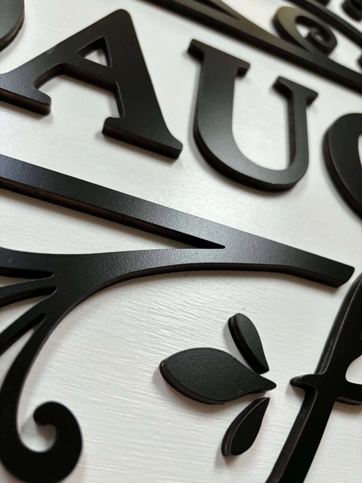 Black and white decorative sign that reads 'Welcome to our home' with stylized floral accents and the words 'Daughter' and 'Foster' partially visible beneath.