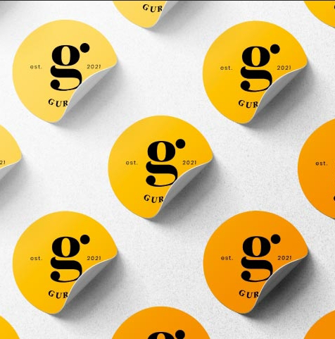 Pattern of yellow and orange circular stickers with black text that read 'est. 2021 g', some stickers are curling at the edges.