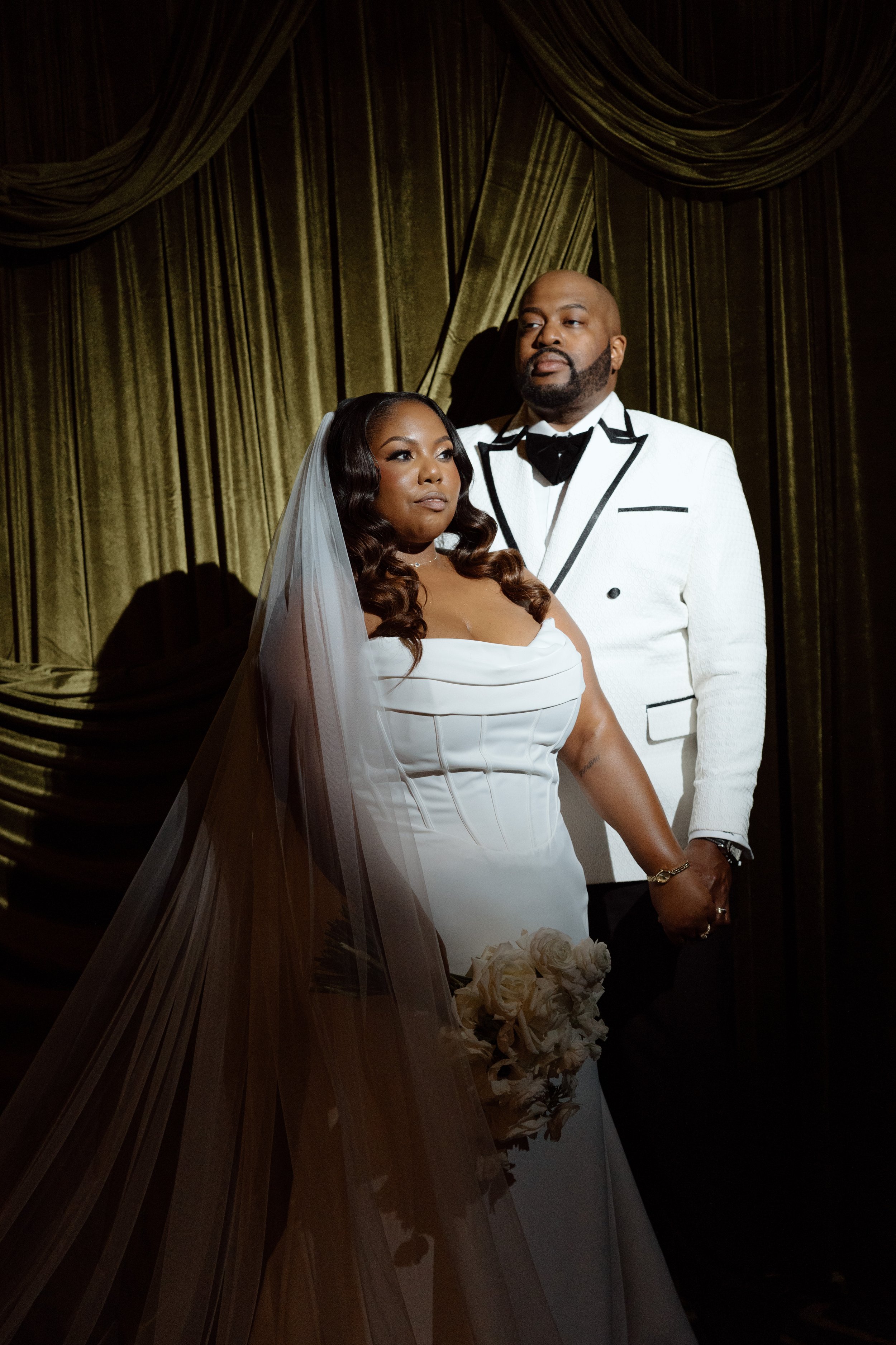 A newly-married couple stands dressed in wedding attire in front of a green wedding drape | Editorial wedding photographer in Richmond and Washington DC