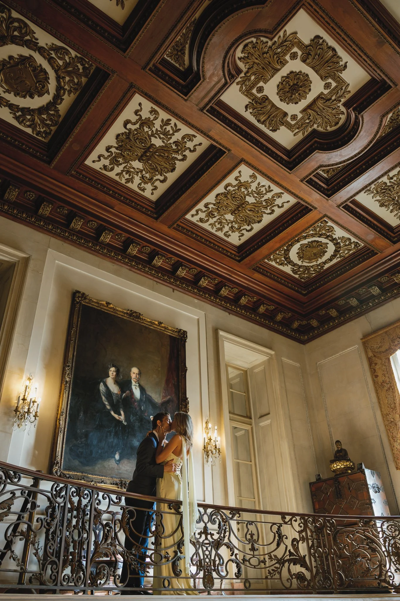 engaged couple leaning over the balcony at the larz anderson house sharing a kiss