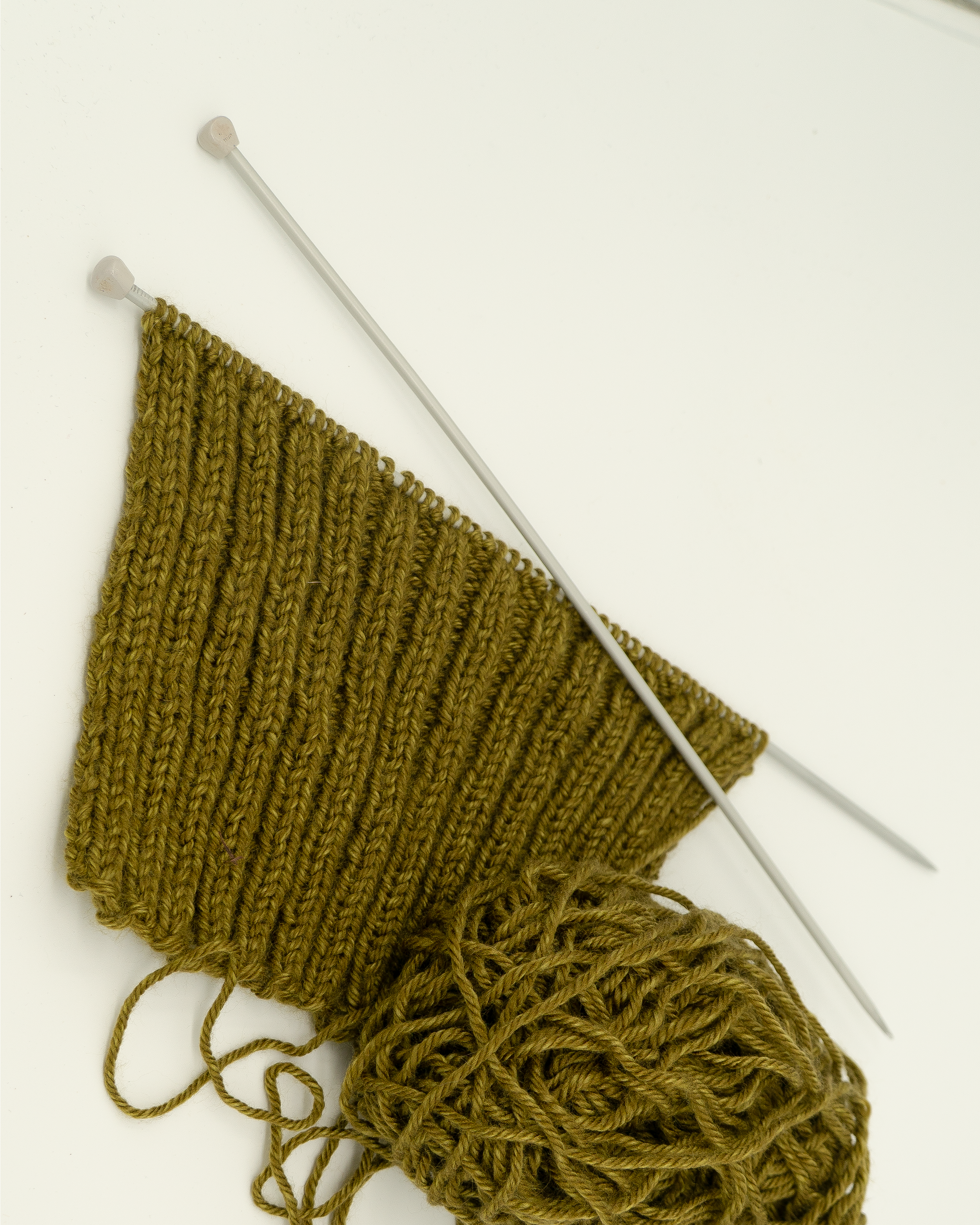 Progress picture of a knitted ribbed leg warmer.