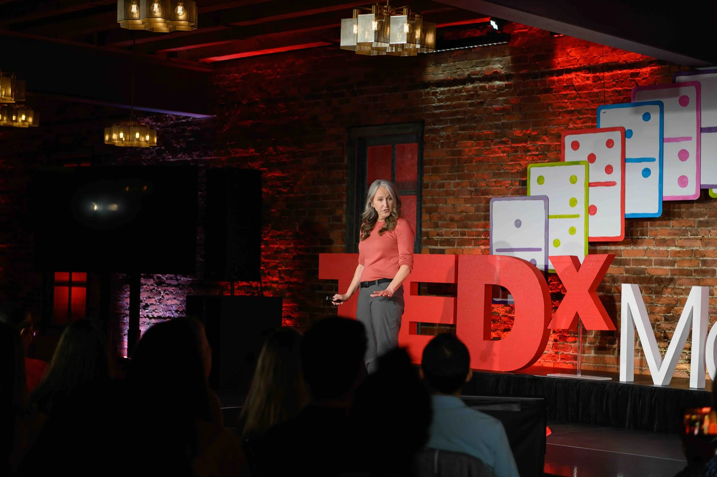 Speaker presenting on the TEDx Montclair stage with the audience in the foreground