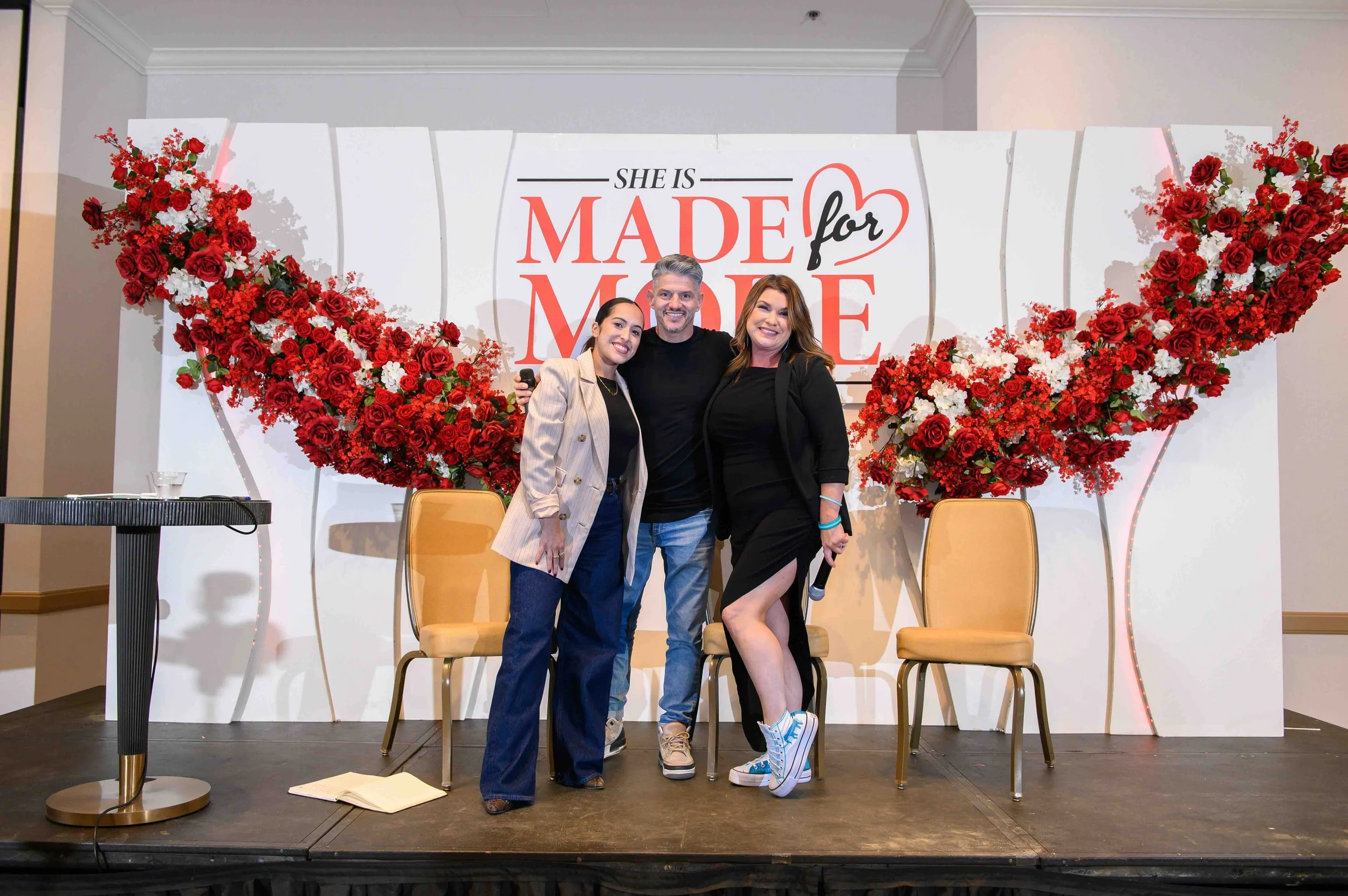 Three people posing together on stage in front of the Made for More backdrop