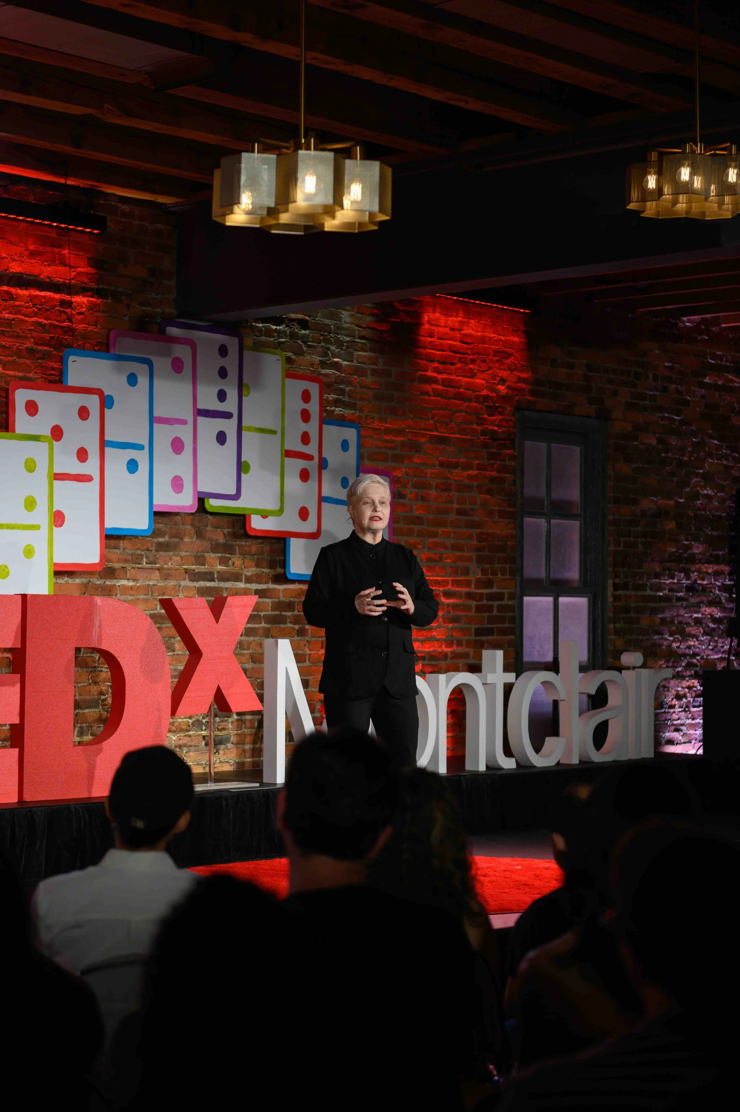 Speaker standing on stage in front of the red TEDx Montclair letters