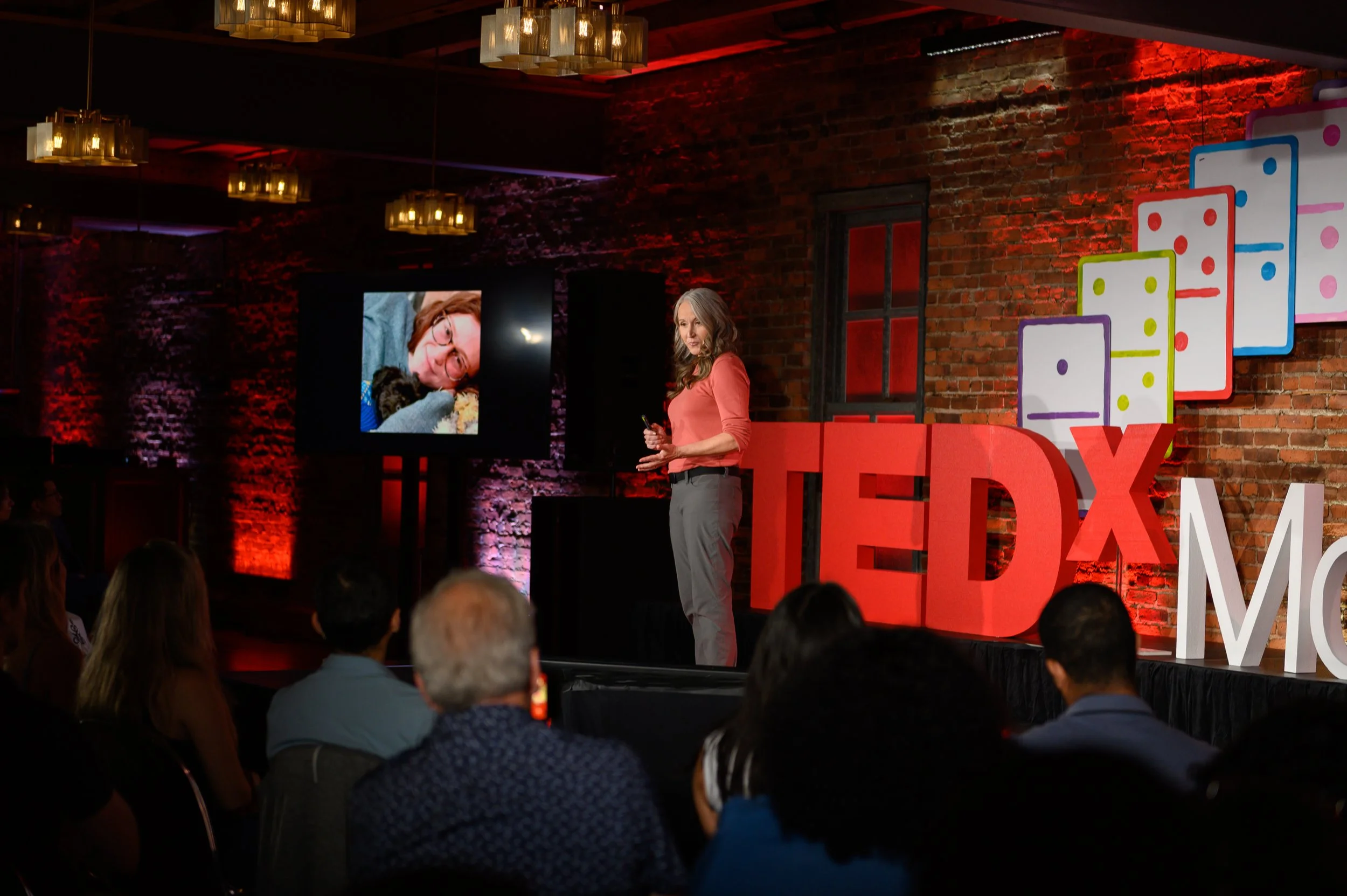 Speaker presenting on stage in front of a screen at TEDx Montclair