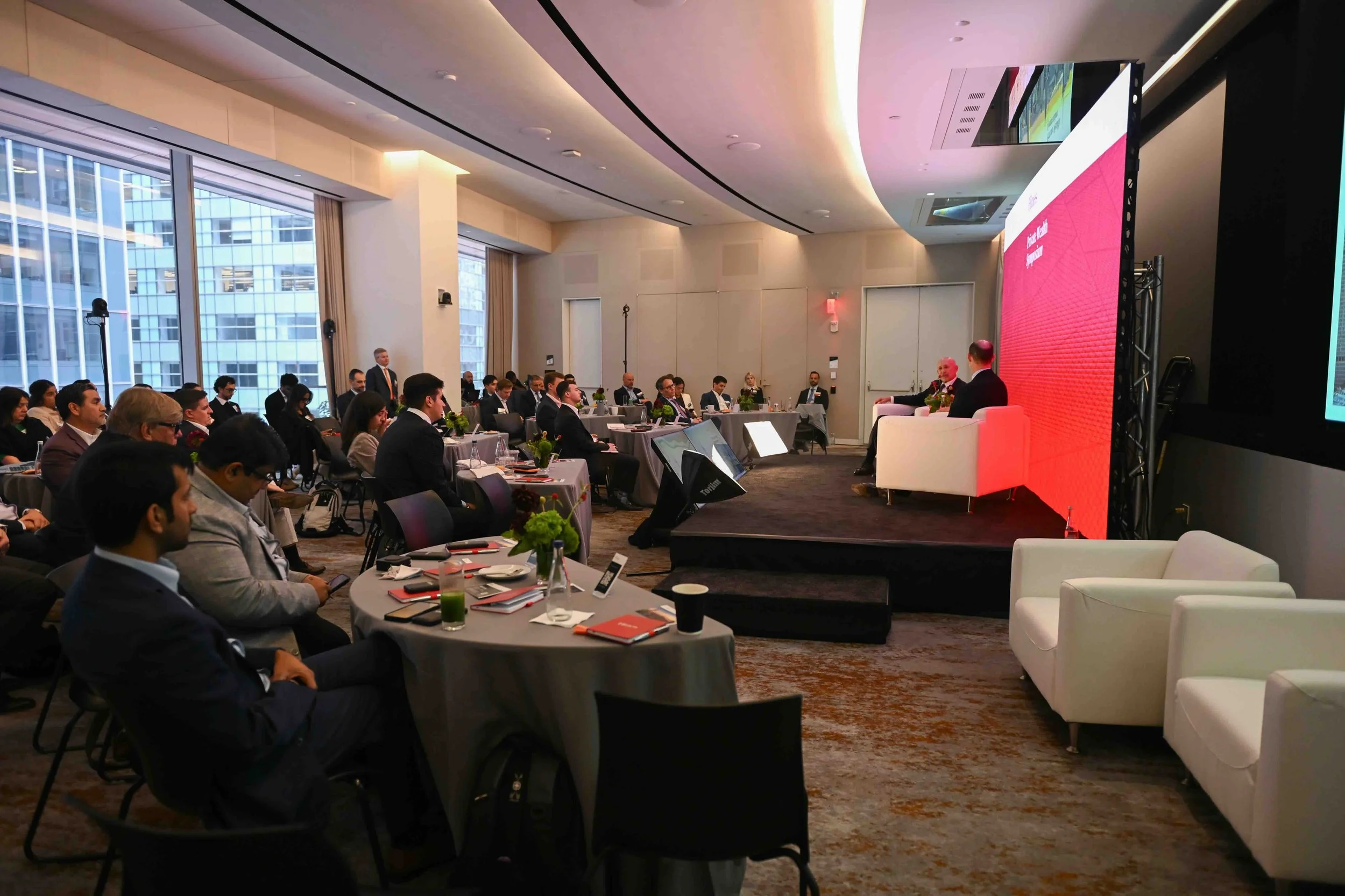 Wide view of the symposium audience seated at tables in the ballroom