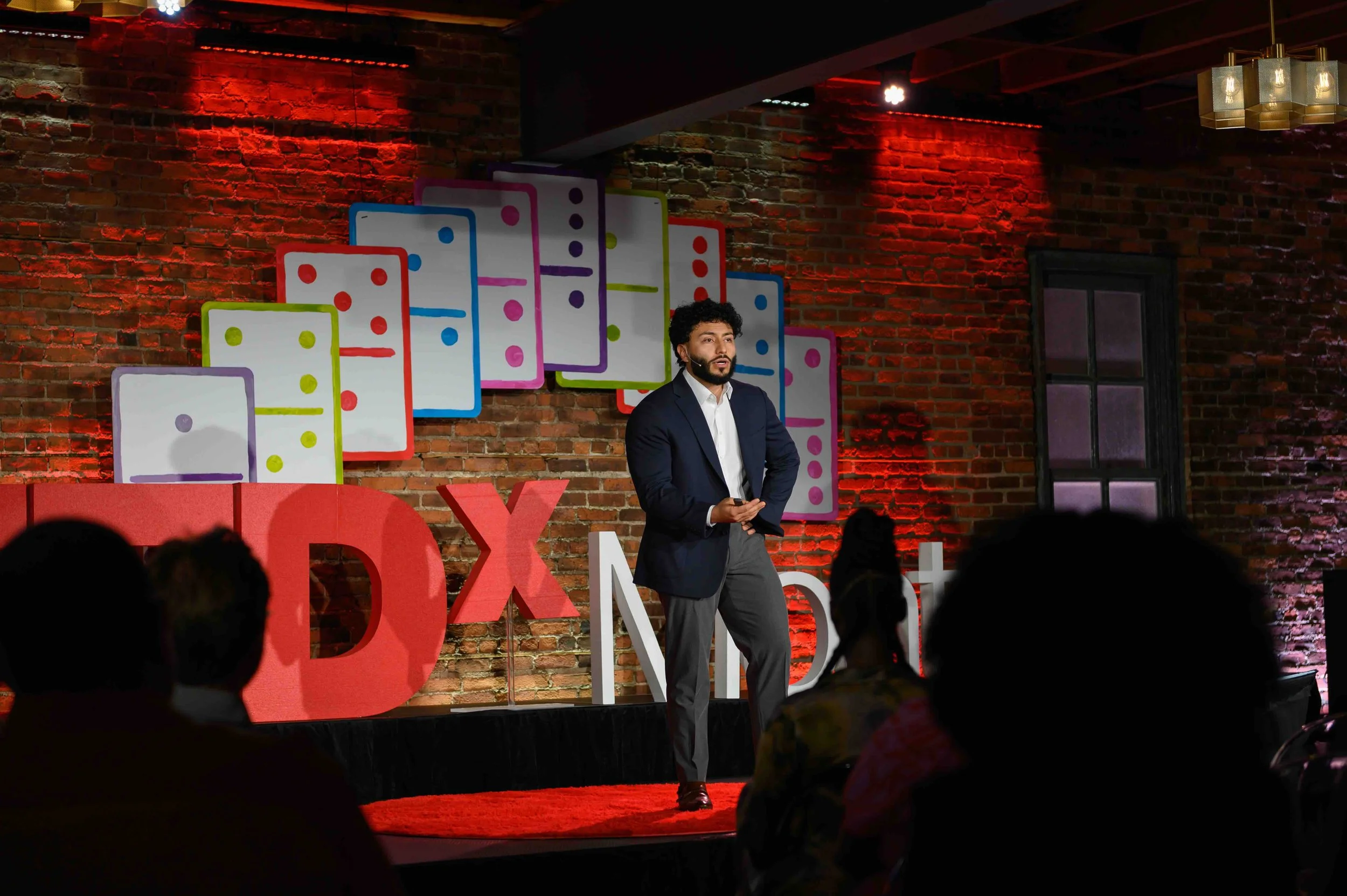 Speaker in dark clothing presenting on stage at TEDx Montclair