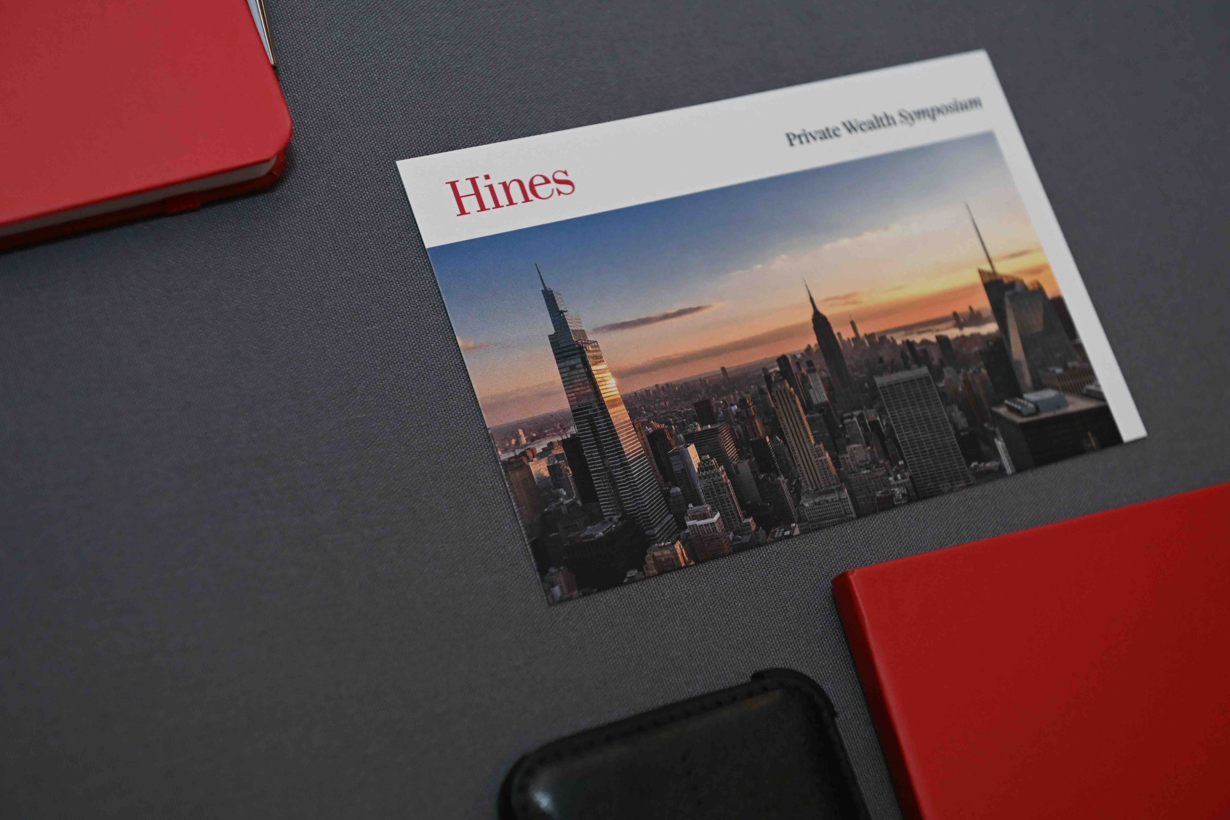 Printed Hines Private Wealth Symposium program on a table with a city skyline cover