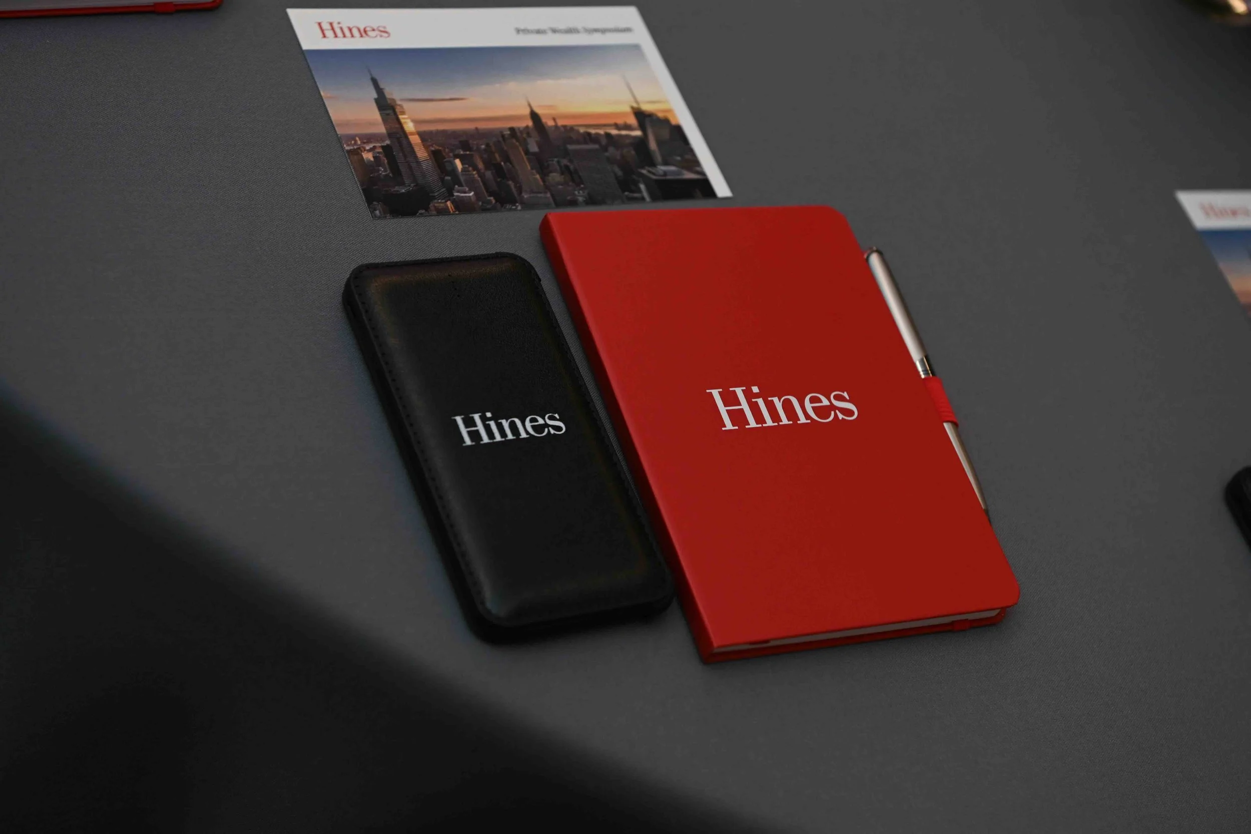 Hines branded red notebook and black accessories on a table at the symposium