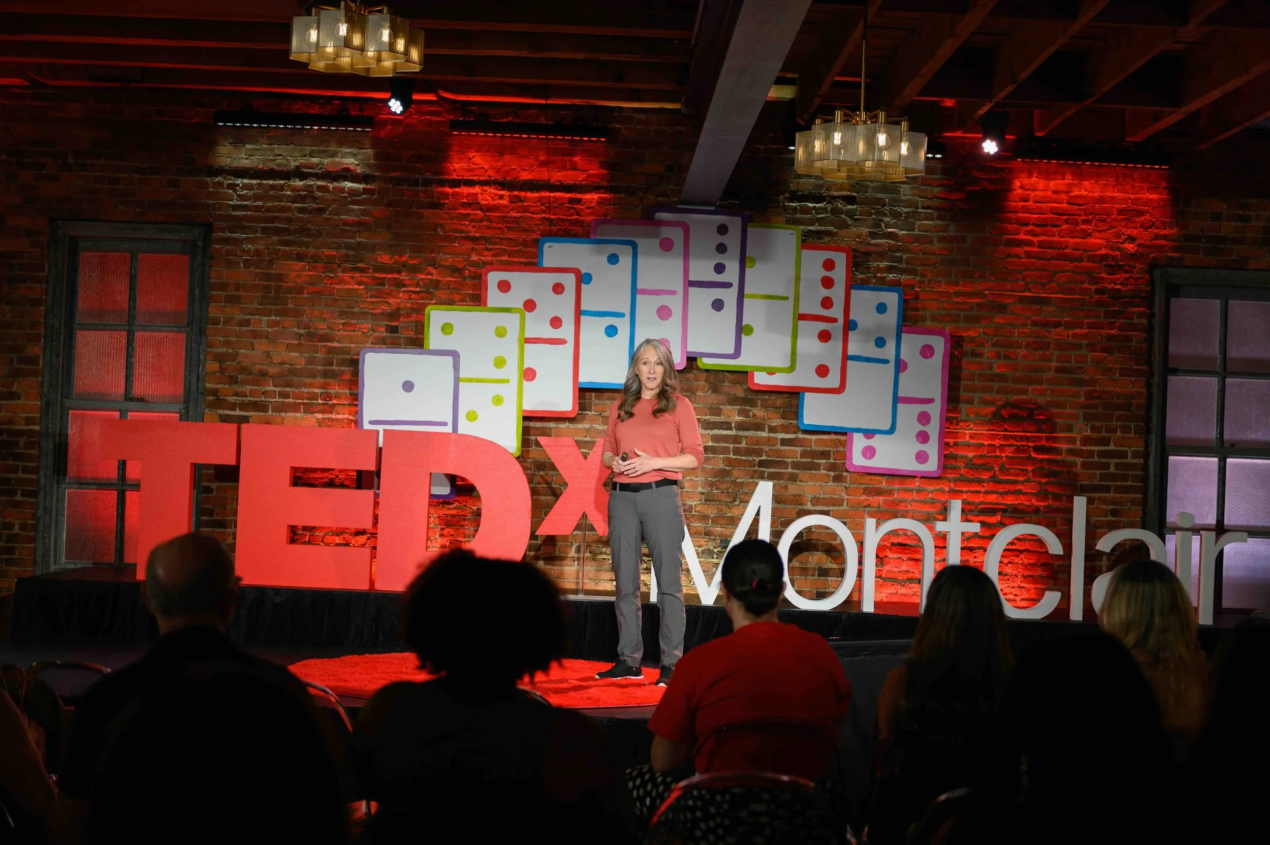 Speaker presenting on stage with the audience seated in front at TEDx Montclair