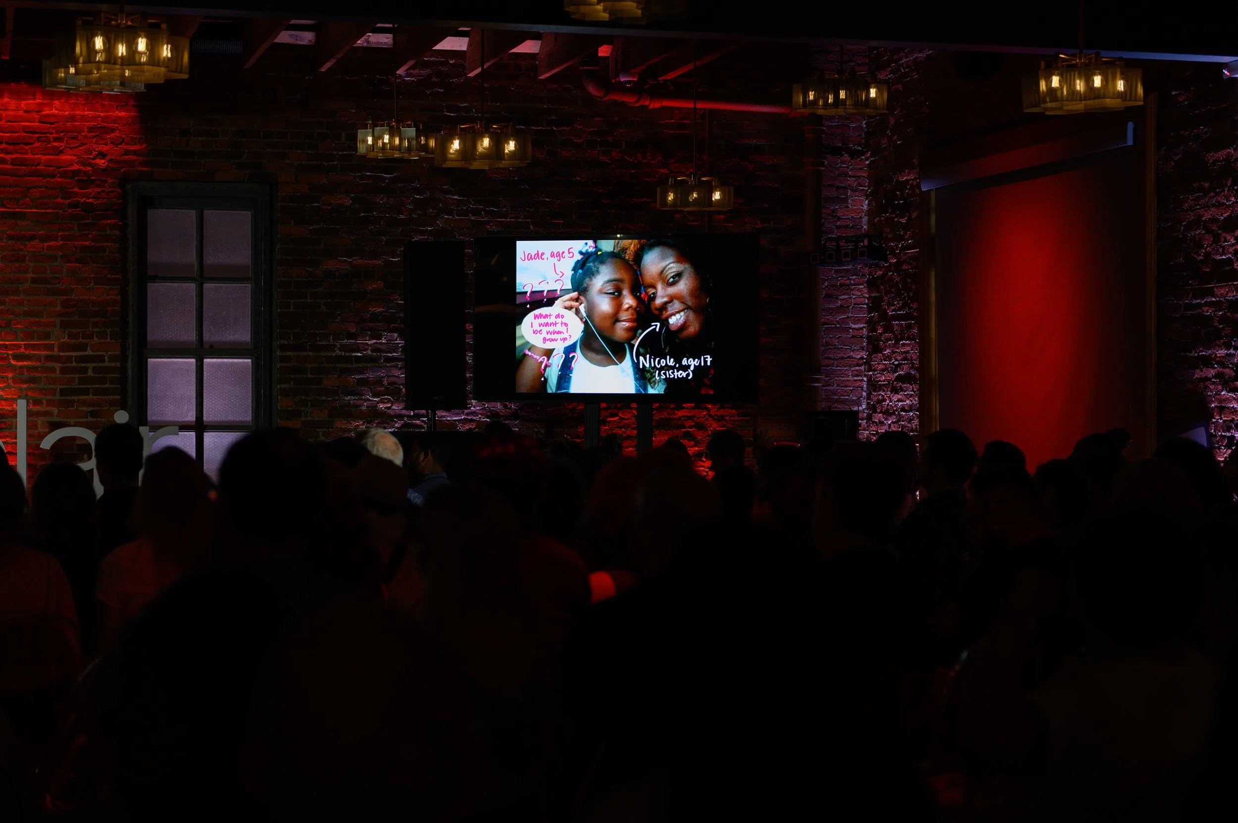 Presentation screen glowing in the darkened TEDx Montclair venue