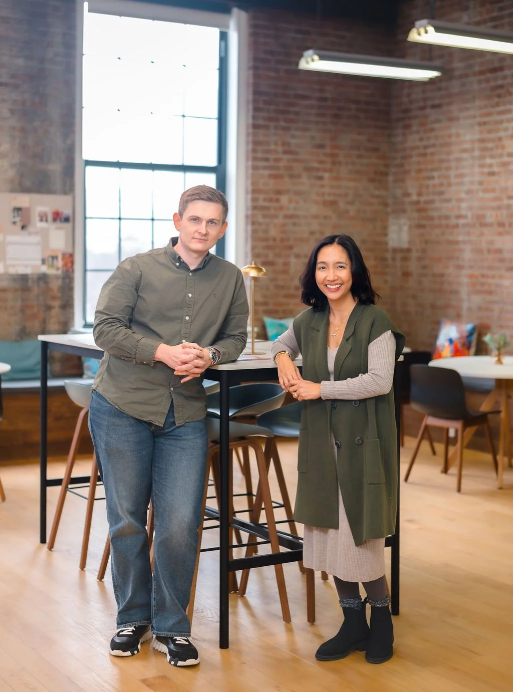 Two team members standing together in a brick-walled office for a Narra Collective brand portrait