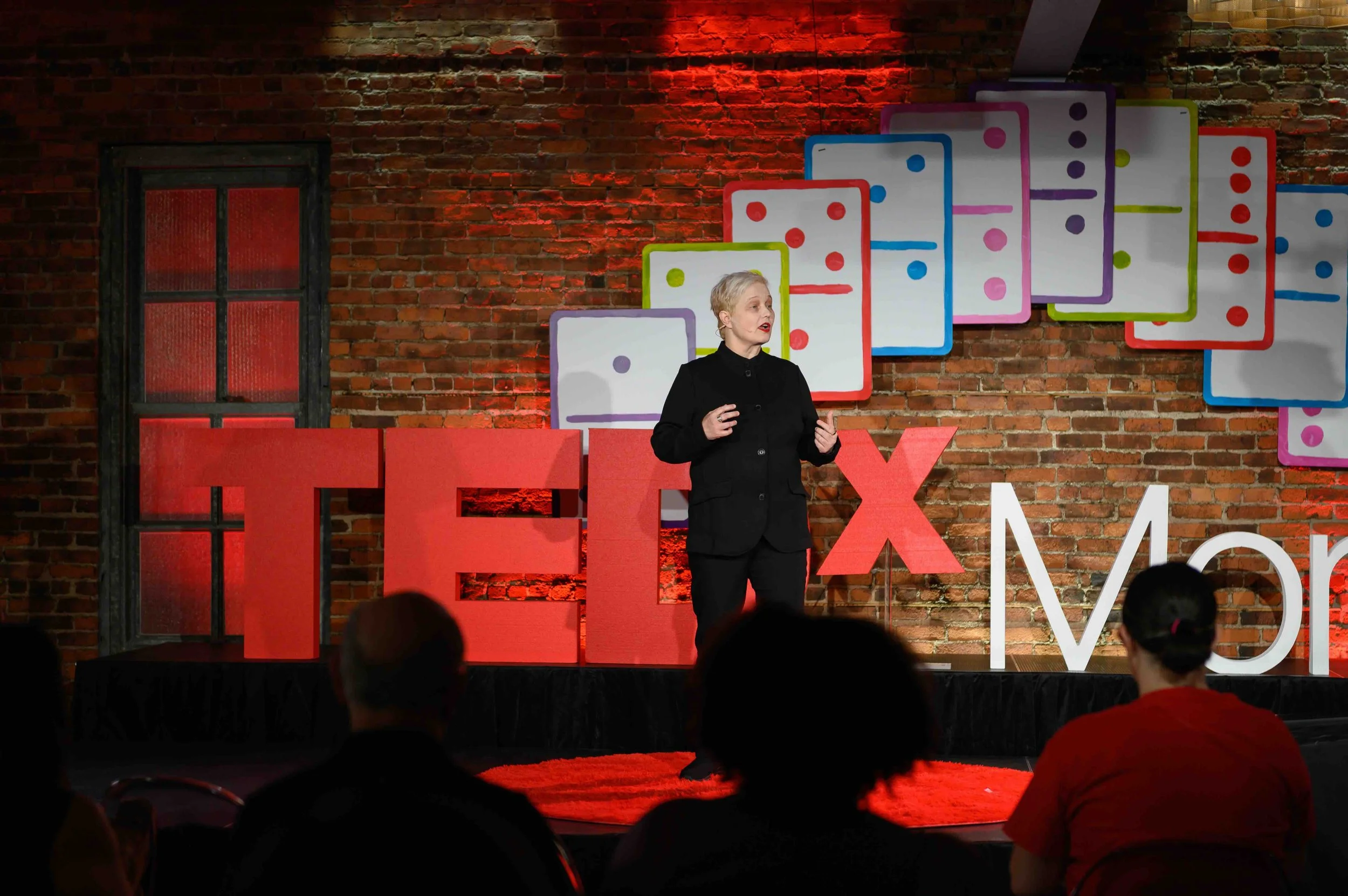Speaker in dark clothing standing on the TEDx Montclair stage