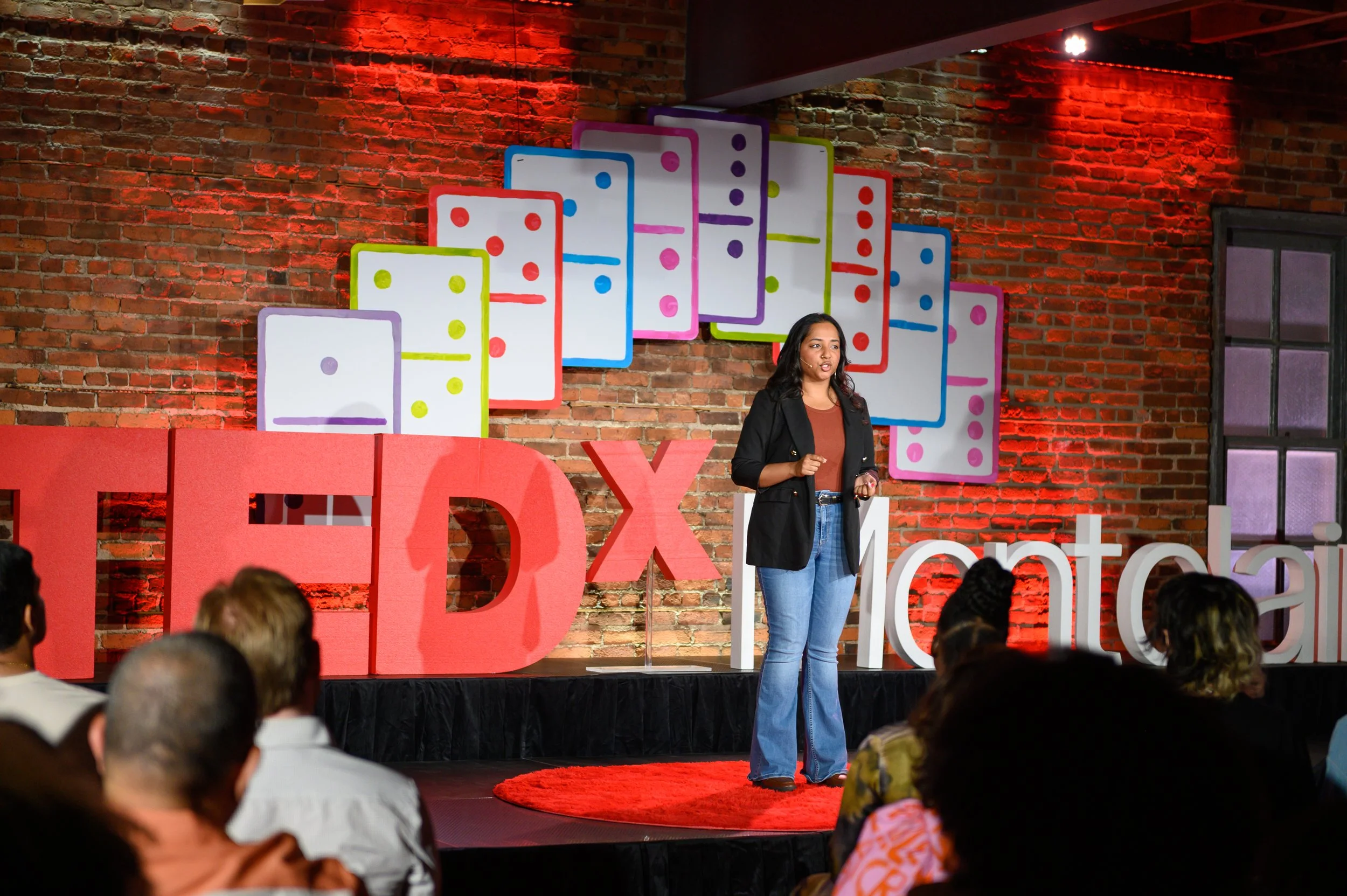 Speaker in dark clothing on the TEDx Montclair stage with a colorful backdrop