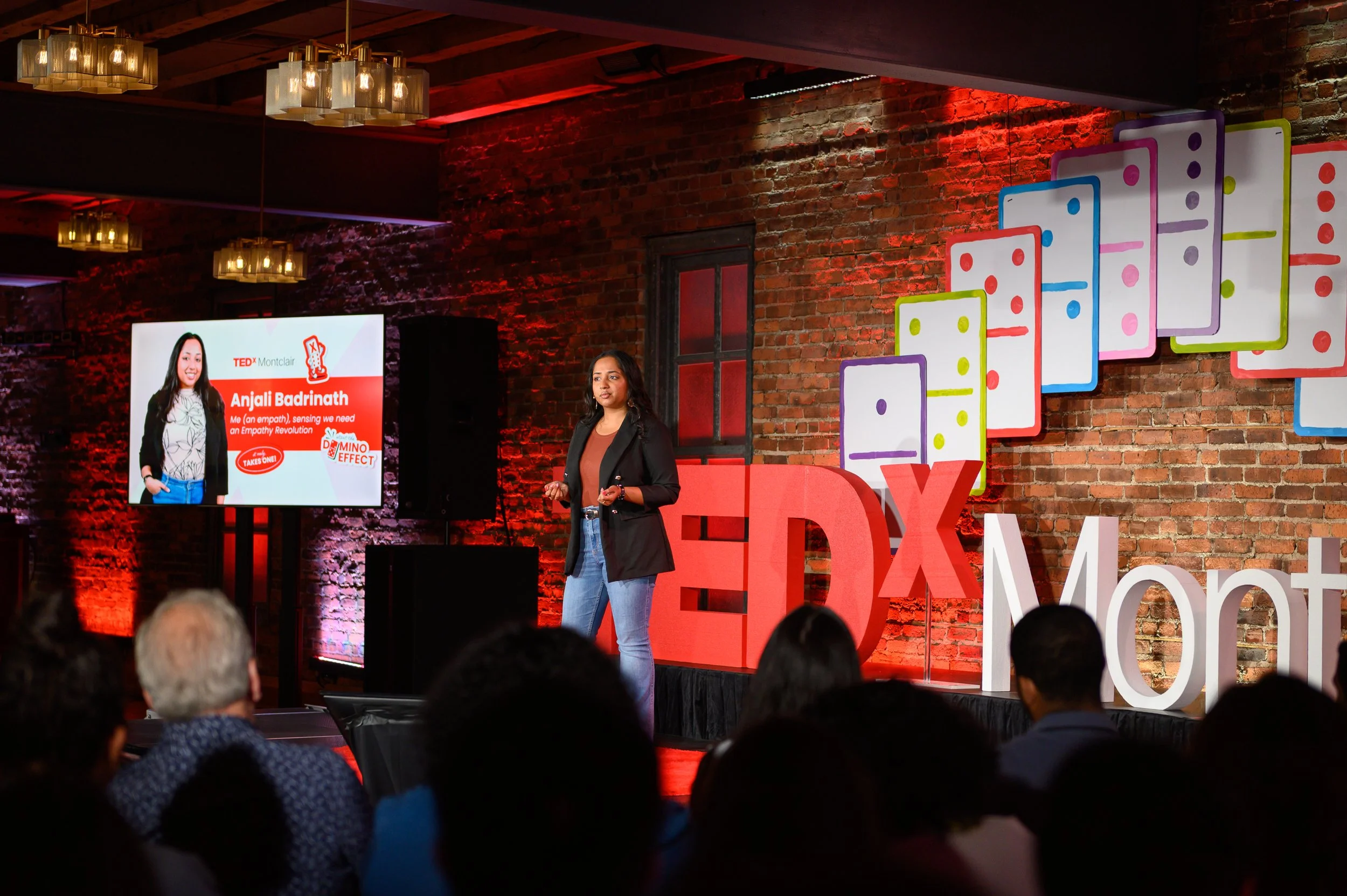 Speaker on stage near a presentation screen at TEDx Montclair