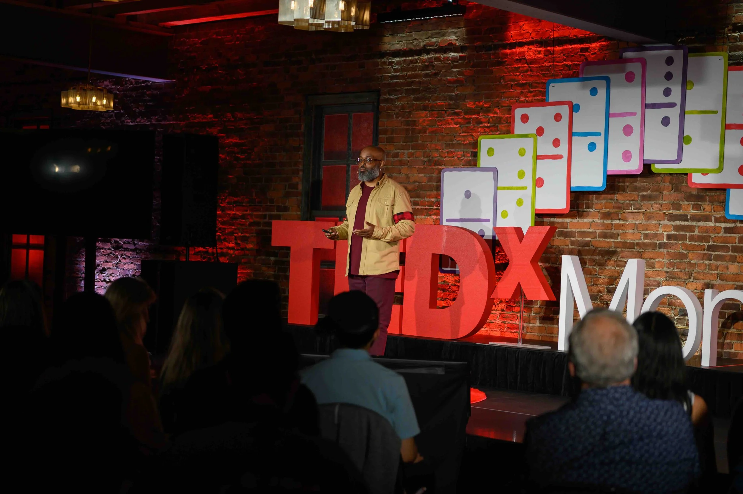 Speaker on stage beside the large red TEDx letters at TEDx Montclair